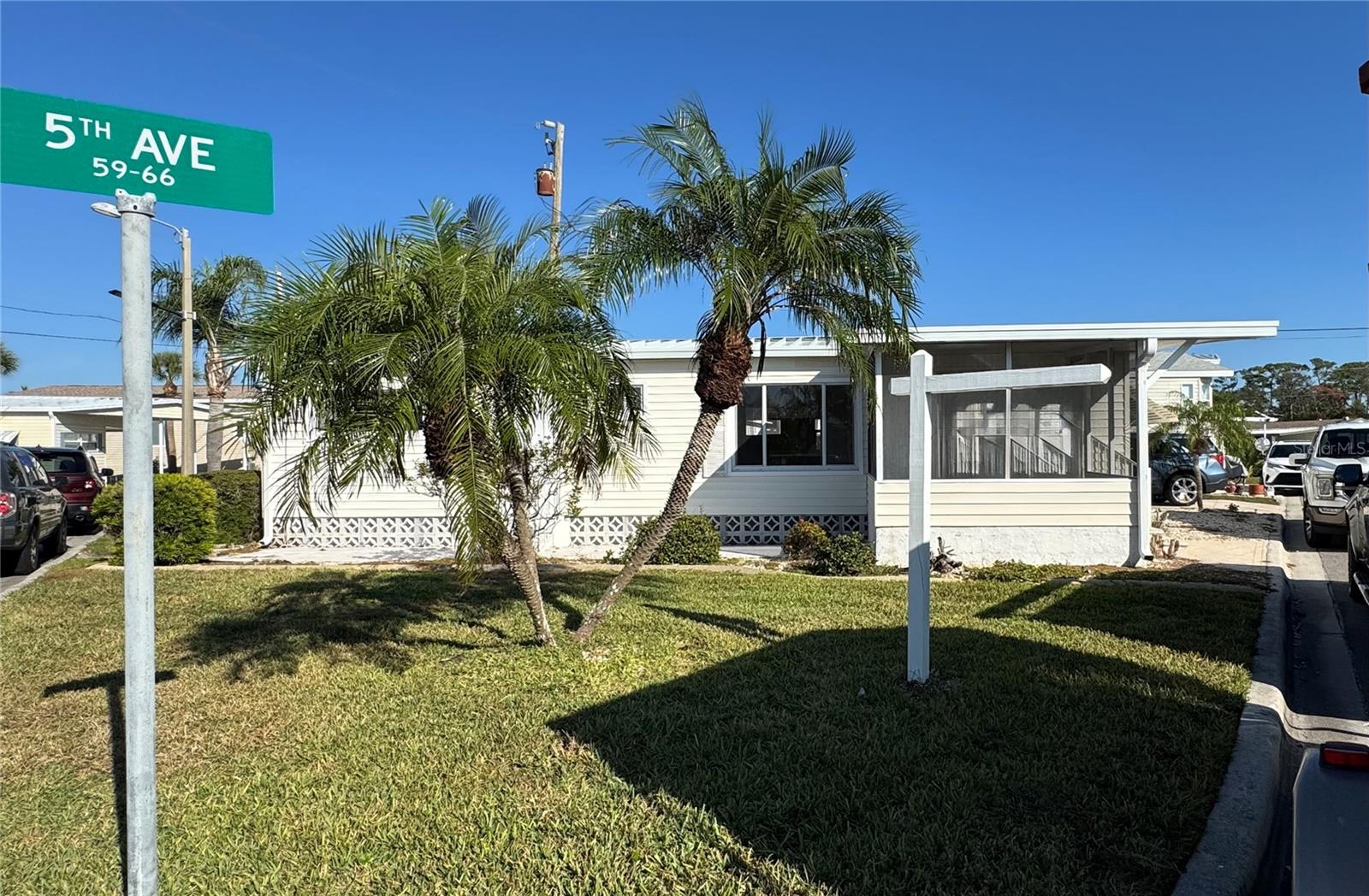 Community Garage Sale February 7. Welcome to Harbor Lights Cooperative — a rare location on Roberts Bay in beautiful Venice, Florida. Here, the purchase of a home and a share means true ownership. This particular home sits on one of the largest lots in Harbor Lights, offering a real yard with plenty of space to expand or simply enjoy the outdoors. It’s located right across the street from a beautifully landscaped park complete with a community dock for fishing, cooking, or catching the evening breeze. The community also features a meeting house, heated pool, tennis, pickleball, woodshop, ceramics, shuffleboard, Sunset Park, and direct access to the Legacy Trail.The community offers no-bridge access to the Gulf of Mexico, with a neighboring marina, available boat slips, and a restaurant/bar just steps away. Publix grocery, Winn Dixie, Churches and Hospital close by. The spacious primary bedroom includes built-in drawers, while the second bedroom offers built-in cabinetry as well. An inviting enclosed lanai provides the perfect spot to relax and watch the world go by.
Additional features include: Metal roof, Carport with long driveway for additional parking, AC 2022 No lot rent! Monthly maintenance $250 includes trash service. The community is known for its friendly residents and full calendar of events. Pets are welcome, boaters are thrilled, and the sunsets are free every day. Harbor Lights Cooperative isn’t just a neighborhood—it’s a waterfront lifestyle waiting for you.