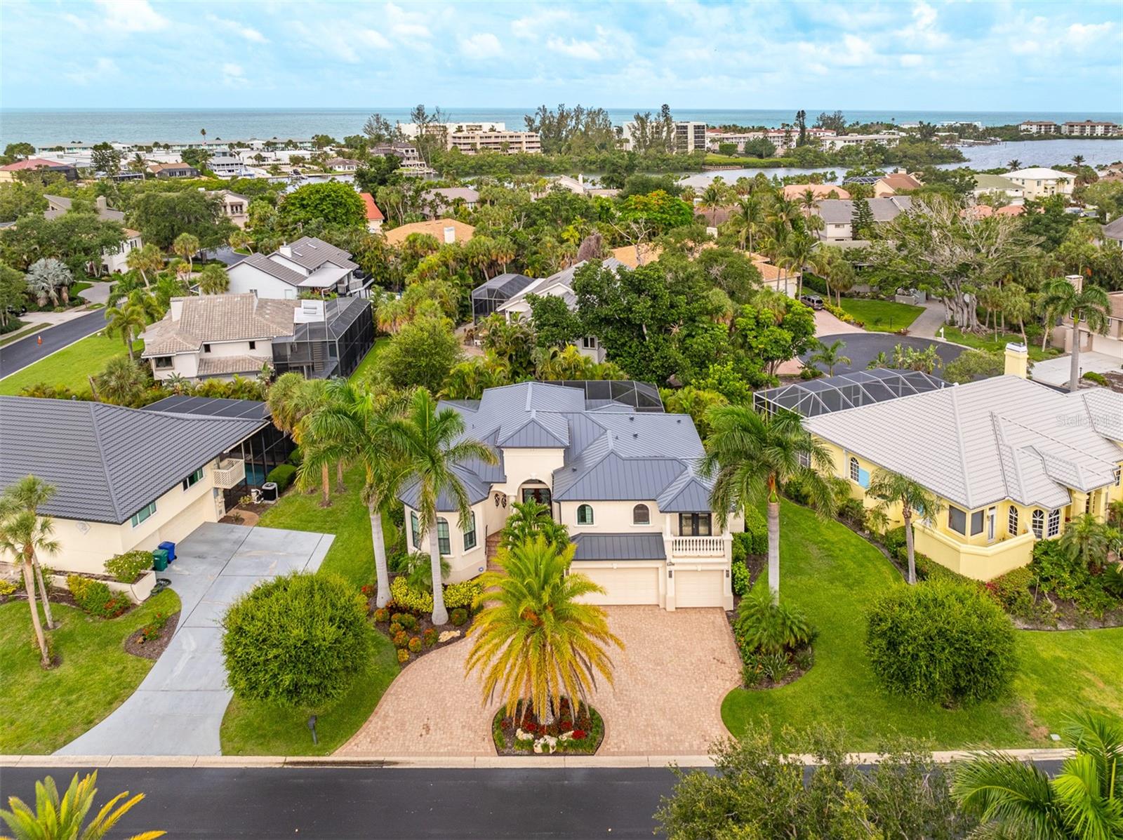 Nestled behind the gates of prestigious Bay Isles on Longboat Key, this exceptional residence offers over 3,000 square feet of thoughtfully designed living space surrounded by lush tropical landscaping and just moments from the Gulf of Mexico. Combining timeless architecture, spacious interiors, and resort-style outdoor living, this home delivers the privacy and elegance that define the Longboat Key lifestyle.

A grand entry welcomes you into an open and inviting floor plan featuring soaring ceilings, abundant natural light, and generous living and entertaining spaces. The expansive great room flows seamlessly into the dining area and well-appointed kitchen, complete with ample cabinetry, extensive counter space, and a convenient wet bar for effortless entertaining.

The first-floor primary suite serves as a private retreat with a spacious bedroom, large walk-in closet, and luxurious en-suite bath. Additional guest bedrooms are thoughtfully positioned for privacy and comfort, while the second floor offers a private guest suite with balcony access—perfect for visitors seeking their own space and enjoying tropical views.

Designed for year-round enjoyment, the screened outdoor living area is a true highlight. Relax poolside in the sparkling heated pool and spa, entertain under the covered lanai, or unwind amidst the lush tropical surroundings that create a secluded backyard oasis.

Located within the highly sought-after Bay Isles community, residents enjoy 24-hour gated security, beautifully maintained grounds, and exclusive access to the private Bay Isles Beach Club on the Gulf of Mexico. Just minutes away are the Longboat Key Club's championship golf courses, tennis facilities, marina, waterfront dining, boutique shopping, and renowned St. Armands Circle.

Offering the perfect blend of luxury, privacy, and coastal convenience, this exceptional Longboat Key residence presents a rare opportunity to enjoy one of Sarasota's most desirable island lifestyles.