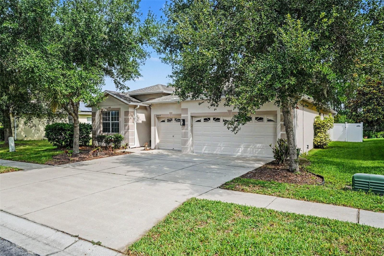 Tucked inside the gated Live Oak Preserve community in New Tampa, this single-story 4-bedroom, 3-bath home offers 2,258 square feet of flexible, livable space on a lot with mature trees behind and no rear neighbors, with a pond view just off to the side. A large living room anchors the home, opening into an expansive flex space — game room, media lounge, playroom, or all three, giving you options most homes in this price range simply don't have. The kitchen is genuinely oversized, with ample cabinetry, generous counter space on every side, and a kitchenette area that makes casual meals and morning routines a little easier. The bedroom layout is one of this home's strongest assets: the primary suite sits privately in the back of the home with room to breathe, while a junior suite near the front entry, separated by a pocket door, offers its own sense of independence, whether for a guest, a multigenerational arrangement, or someone who simply keeps different hours. Outside, a fully fenced backyard shaded by mature trees is ready for your own vision. Live Oak Preserve is a private, gated community on 1,300 acres with 362 acres of wetland preserves and resort-style amenities including a clubhouse, pool with lap and splash areas, fitness center, lighted tennis and pickleball courts, basketball, volleyball, and walking trails. Bruce B. Downs Boulevard, I-75, and I-275 put you minutes from the Shops at Wiregrass, Tampa Premium Outlets, downtown Tampa, USF, and the Gulf beaches. Schedule your showing today.
