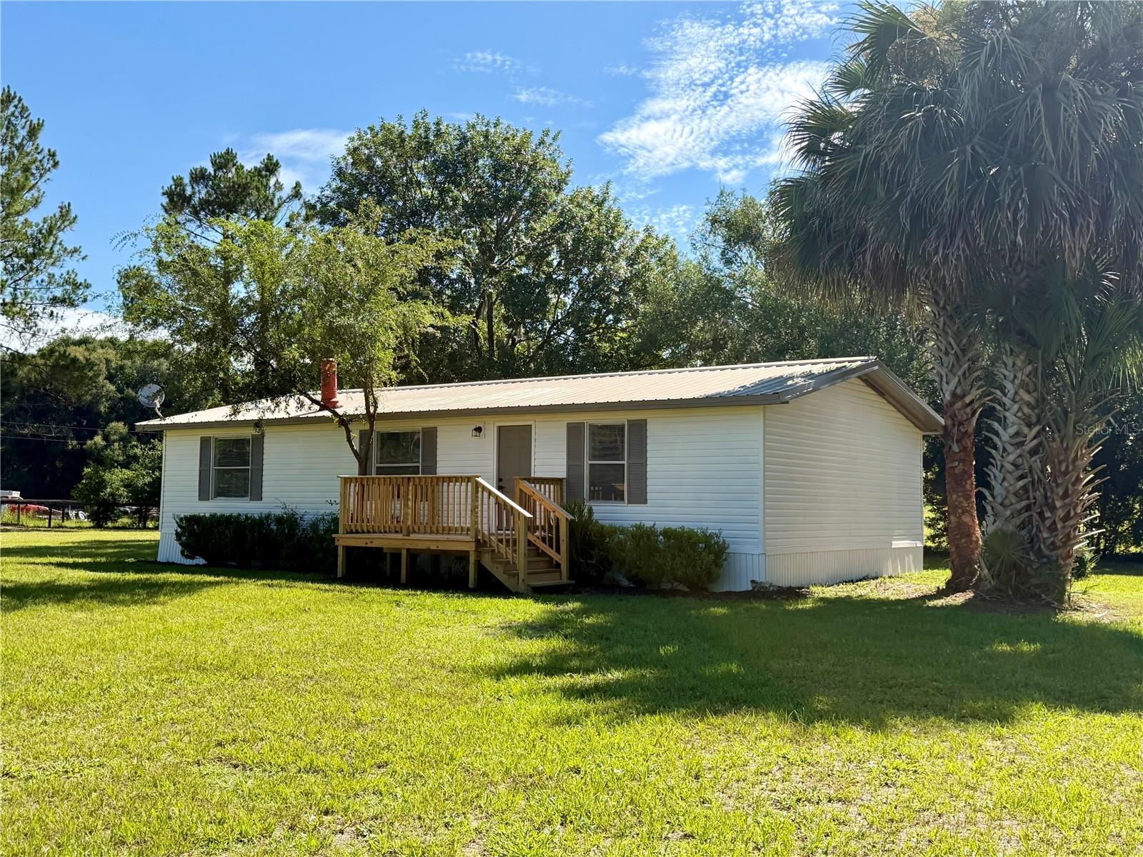 Rare opportunity to own this fully renovated property with A-1 Agricultural zoning on 3.17 private, fenced, and gated acres! Bring your horses, cattle, chickens, and all your outdoor toys—this property offers the freedom of country living with NO HOA and endless possibilities. This beautifully updated 3-bedroom, 2-bath has been completely remodeled and is move-in ready, featuring new luxury vinyl flooring throughout, fresh interior and exterior paint, new kitchen cabinets, granite countertops, brand-new stainless steel appliances, new lighting throughout, beautifully renovated bathrooms with new vanities, and a new A/C and water heater (2026). The spacious, open living area is filled with natural light and features a beautiful stone fireplace, while the inviting front porch and back porch provide the perfect place to relax and enjoy the peaceful surroundings. Outside, you'll find a large metal barn/workshop with a concrete slab foundation, a spacious storage building with an attached lean-to, a utility shed, a charming wooden outbuilding, and plenty of room for equipment, trailers, RVs, boats, gardening, or creating your dream mini farm. Surrounded by mature trees and offering exceptional privacy, this property combines modern updates, functionality, and peaceful country living on over three acres. Properties like this don't come around often—schedule your private showing today!