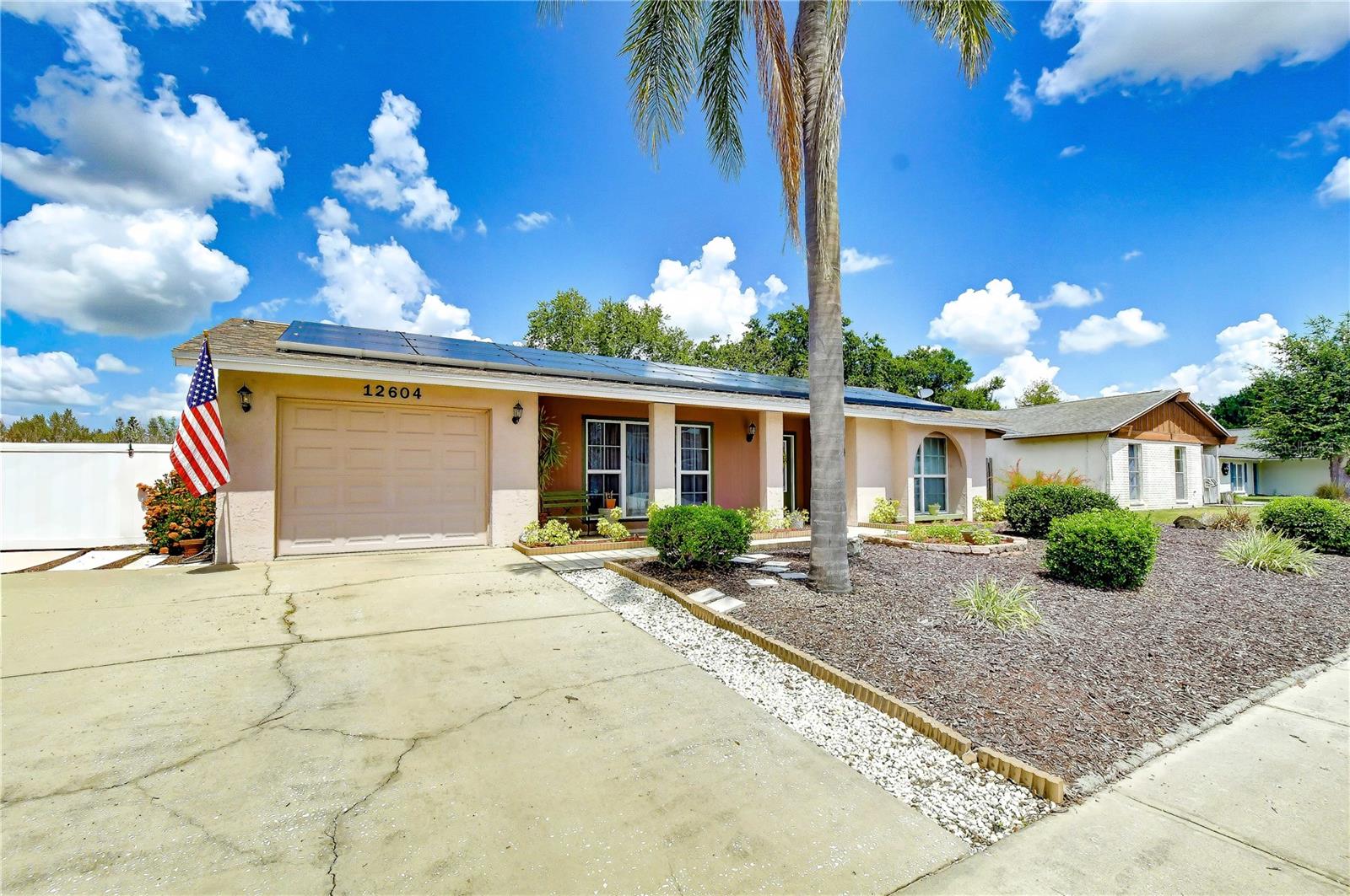 From the moment you arrive, you'll appreciate the home's exceptional curb appeal featuring a covered front porch, mature palm trees, lush landscaping, neatly manicured shrubs, decorative mulch beds, an attractive arched front window, front door with elongated leaded glass inserts, and an oversized two-car-wide driveway leading to the attached one-car garage. A roof-mounted solar energy system installed in February 2026 enhances energy efficiency.
Inside, soaring vaulted ceilings with a decorative exposed beam and abundant natural light create an inviting sense of space throughout the open living and dining rooms. Wood-look ceramic tile flooring, a large picture window overlooking the front yard, and sliding glass doors leading to the screened lanai make these spaces perfect for both everyday living and entertaining.
The beautifully updated kitchen is designed with both style and functionality in mind, featuring raised-panel wood cabinetry, granite countertops, a decorative tile backsplash, breakfast bar seating, track lighting, and an adjacent cozy café area with sliding glass doors that provide relaxing views of the pool and backyard.
The spacious family room offers wood-look ceramic tile flooring, a ceiling fan, and a comfortable gathering space with convenient access to the secondary bedrooms and guest bath.
The private owner's suite provides a peaceful retreat with generous room for furnishings, a ceiling fan, double closets plus an additional storage closet, and a beautifully remodeled en-suite bath showcasing a granite-topped vanity, custom cabinetry with a built-in storage tower, an oversized walk-in tiled shower with decorative Listello accent, shampoo niche, and contemporary finishes.
Outdoor living is where this home truly shines. Enjoy year-round Florida living from the expansive screened lanai with decorative stone flooring, kickplates, and plenty of room for outdoor dining or relaxing while overlooking the sparkling swimming pool. Beyond the pool, the large fully fenced backyard offers exceptional privacy and includes a charming pergola, creating the perfect setting for entertaining, gardening, pets, or simply enjoying the outdoors.
Additional improvements provide peace of mind, including a new roof (2019), replacement HVAC system (2022), 50-gallon electric water heater (2022), the pool was resurfaced 2021, replacement ductwork (2016), and 10 replacement windows plus two sliding glass doors (2007). The attached one-car garage also includes a convenient laundry area and additional storage space.
Zoned for highly regarded Sickles High School and conveniently located near shopping, dining, parks, the Veterans Expressway, Tampa International Airport, and the many amenities of Citrus Park and Carrollwood areas. This well-maintained home combines thoughtful updates, energy efficiency, and comfortable Florida living.
Don't miss this exceptional opportunity to own a move-in-ready home with major updates, a private pool, a spacious fenced backyard, and energy-saving solar benefits in one of Tampa's most desirable locations. Schedule your private showing today and discover everything this wonderful home offers!