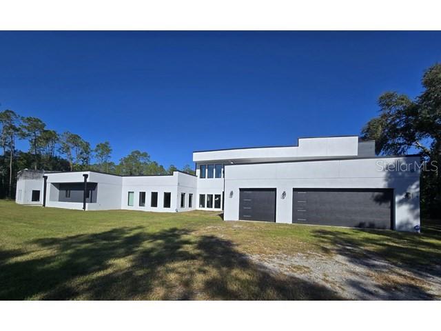 Set on more than four acres in a private, natural setting, this contemporary Lutz estate presents a unique opportunity to complete a large-scale modern residence tailored to the buyer’s vision. The property offers over 8,000 square feet of planned living space, with the primary structure and major systems already in place. The existing framework allows for six bedrooms and six bathrooms, expansive living areas, and a dramatic kitchen layout designed to accommodate two oversized waterfall islands, commercial-grade appliances, and custom cabinetry. Walls of glass in the main living area are designed to maximize natural light and capture views of the property’s two private ponds. The home is not fully completed and will require additional construction and finish work. Infrastructure already installed includes smart-home wiring, prewiring for a theater room and recreation space, integrated audio and surveillance systems, and multiple rooftop and balcony areas awaiting final completion. A concealed studio space offers flexibility for conversion into a guest suite or secondary primary bedroom. Partial high-end finishes have been installed throughout, including wood-look porcelain tile, modern tile accents, stainless fixtures, and rock-splash flooring. The property is supported by commercial-grade water filtration and septic systems, dual Generac generators with automatic transfer switches, and a large propane tank. Offered as-is, this property is well suited for buyers seeking privacy, acreage, and the opportunity to complete a custom modern estate in Lutz.