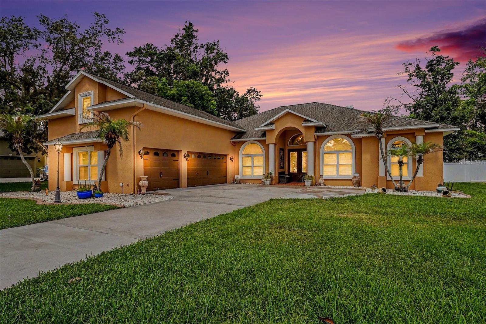 Executive Home in Valrico Forest — Refined Living, Built to Entertain. Welcome to 2305 Valrico Forest Dr, a 5-bedroom, 4-bath, 3,278 sq ft executive estate set behind a manicured lawn and mature oak canopy in one of Valrico’s most established communities. Arched architectural windows, a columned portico, and carriage-style garage doors give the home a presence that announces itself the moment you pull up — and an extensive list of 2026 updates means timeless architecture paired with brand-new finishes. Step through the leaded-glass double doors into a soaring foyer framed by stately columns and arched openings. Formal living and dining rooms set the tone, while the heart of the home opens into a true great room with vaulted, beamed ceilings, a fireplace, and seamless flow into a chef-worthy kitchen. Granite counters, an oversized center island with bar seating, abundant wood cabinetry, a walk-in pantry, a new wine fridge, and a sunlit breakfast nook make daily life and weekend hosting equally effortless. The kitchen also boasts a brand-new range with a double oven and built-in air fryer. The showstopper? A dedicated home theater room wired and finished for the full cinema experience, complete with its own built-in bar and concessions counter — plus a full bath just steps away, freshly appointed with a new vanity, cabinet, and faucet. Buyers seeking a fifth true bedroom will appreciate that this room was originally built as an en-suite bedroom; the closet remains in place for easy conversion back if desired. A separate flex room currently used as a craft/office (with a stylish picture-ledge feature wall that conveys) adapts to whatever life calls for. The owner’s retreat is a private sanctuary: tray ceiling, sitting area, and a spa-inspired en suite with a newly updated vanity, fresh cabinetry, designer backsplash, and new faucet, plus a soaking tub, frameless walk-in shower, and generous walk-in closet. Three additional bedrooms and beautifully appointed full baths give family and visitors room to spread out, including a Jack-and-Jill bath with new vanities and faucets and a coastal-themed guest bath. Brand-new carpet has been installed in all bedrooms. Step outside and the home truly comes alive. A massive panoramic screen enclosure houses the heated pool with raised spa and stacked-stone waterfall, surrounded by expansive brick-paver decking with ample room for lounging and entertaining. The outdoor living area features a covered entertainment wall, built-in bar with sink, and new ceiling fans throughout — designed for year-round Florida living. A pool-side water closet on the lanai adds true convenience for entertaining. Beyond the cage, a pergola-covered patio and vinyl-fenced backyard with mature shade trees offer even more privacy. Additional highlights: tile and hardwood flooring in the main living areas, a newly updated laundry room with new cabinetry, oversized sink, and faucet, new exterior front and garage side doors, new garage door openers with remotes, and a new gas water heater. Centrally located minutes to top-rated Valrico schools, shopping, dining, I-4, the Crosstown, and a short drive to downtown Tampa, MacDill AFB, and Gulf beaches. Refined, private, and unmistakably move-in ready. Schedule your private tour today.