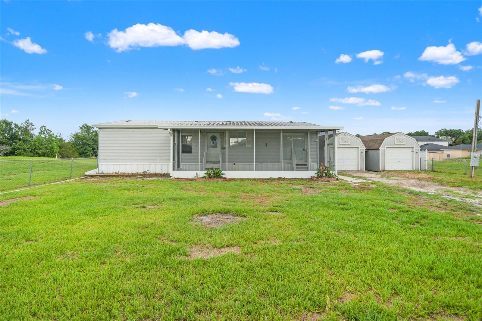 Welcome to 504 Manilla Ln, Winter Haven, FL! This 3-bedroom, 2-bath manufactured home sits on a fully fenced and gated 0.5-acre lot, offering privacy, space, and plenty of potential. The property features chain-link fencing around the front yard with vinyl fencing along the rear of the property, creating a secure and private outdoor space.

Inside, you'll find a desirable split-bedroom floor plan with a spacious primary suite, comfortable living room, dedicated dining area, breakfast nook, pantry, and interior laundry room. The kitchen includes a dishwasher, and a range will convey with the sale but is not currently installed.

One of the standout features is the oversized screened front porch spanning nearly the entire length of the home—an ideal space to relax, entertain, or enjoy Florida's beautiful weather year-round. The property also includes 2- 10x20 outdoor storage buildings, large enough to accommodate a small vehicle, workshop space, or additional storage needs.

Conveniently located near Winter Haven's popular attractions, including LEGOLAND® Florida Resort, the Chain of Lakes, parks, shopping, dining, and entertainment. Enjoy easy access to outdoor recreation and all that Central Florida has to offer. Property is being sold as-is.