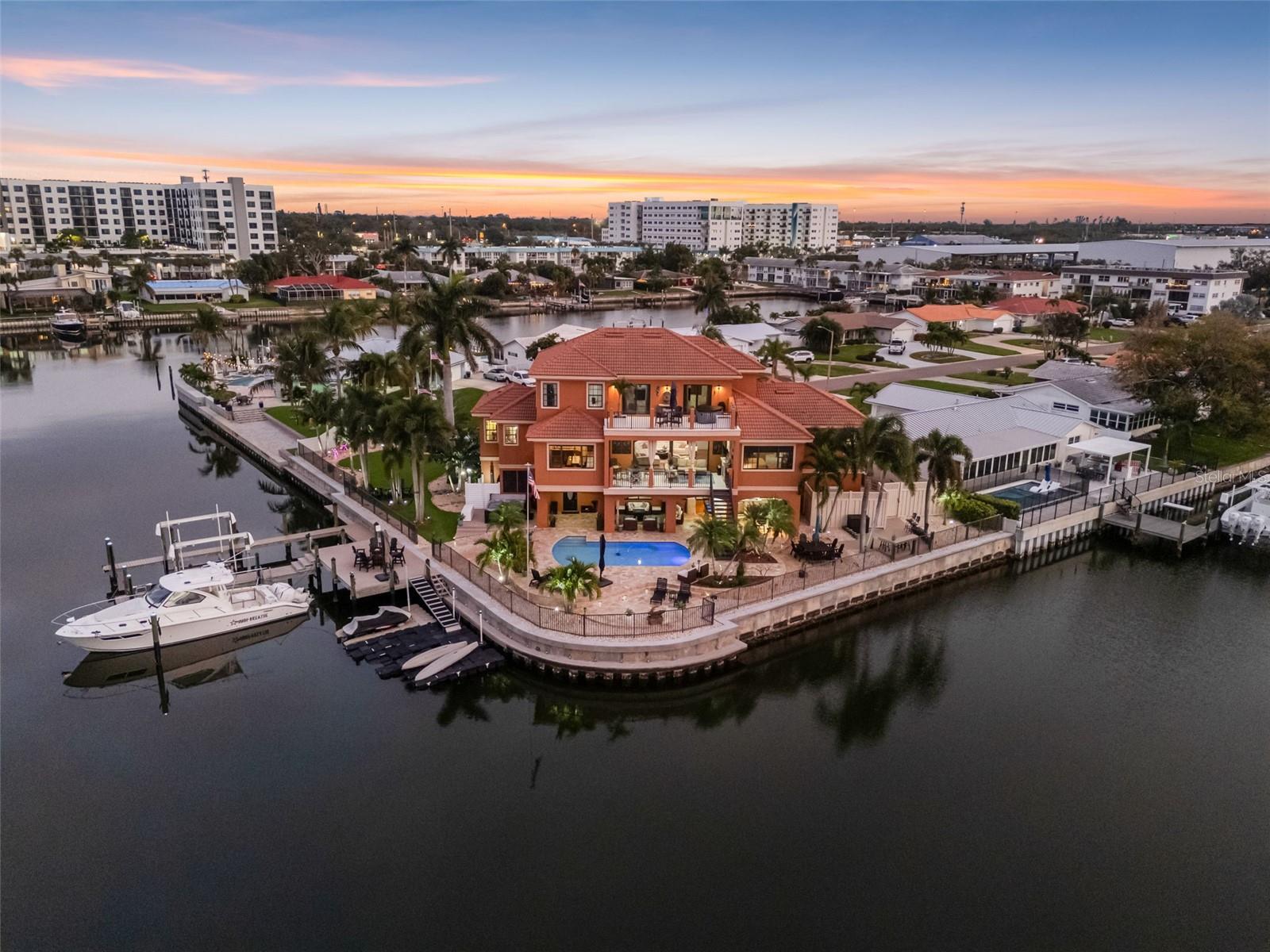 Under contract-accepting backup offers. This exceptional waterfront estate offers an unmatched blend of luxury, functionality and outdoor living boasting an impressive 265 feet of waterfront with deep water access and thoughtfully designed layout ideal for both everyday living and entertaining. This home is a true haven for serious boaters. The Dock set up features a 23K lb boat lift, 800 sq feet of composite surface area, 400 sq ft of floating docks with ramp, a jet ski dock, multiple power sources including 110v, 30amp and 50amp service… all designed for effortless access to the Gulf of America with a short 20 minute boat ride. Nearly every room captures water views, creating a serene backdrop for daily living. A custom elevator servicing all floors brings you to the main level, where soaring ceilings and a wall of sliding glass doors flood the space with natural light and frame the expansive waterfront. The chef’s kitchen serves as the heart of the home, showcasing gleaming granite countertops, a spacious central island, premium appliances, and a walk-in pantry. This residence is as functional as it is beautiful, offering new AC units, new water heaters, hurricane-rated PGT windows and sliders, 400-amp electrical service with surge protection, whole-house soft water, and a natural gas generator—all serviced regularly for turnkey peace of mind. Unwind in the dedicated media/recreation room, or retreat to the luxurious primary suite, a private sanctuary featuring dual spa-inspired bathrooms and custom walk-in closet. Additional bedrooms, a home office, and a library/den offer refined, flexible spaces to suit your lifestyle.  Outdoor living takes center stage with over 1200 sq ft of covered deck space plus a 3rd floor sun deck. Enjoy a custom pool with 1300 sq ft of travertine deck space, gas heater, a 6-person hot tub, and a full natural-gas outdoor kitchen with grill, double burner, dishwasher, frig, dual bar areas, custom lighting and ample storage. The second-floor deck has a natural-gas fireplace.  The covered decks offer a cozy, year-round gathering space with expansive water views from the protected canal setting—a rare combination of beauty and shelter. The oversized 3-plus-car garage includes a heavy-duty suspended rack system for exceptional storage, a workshop area, space for motorcycles, golf carts, and all your coastal toys. Located just minutes to vibrant downtown St. Pete, and the area’s award-winning beaches, this home delivers the ultimate blend of luxury, lifestyle, and unmatched boating amenities. With premium upgrades, panoramic water views, and every detail thoughtfully designed, this is a rare opportunity to live the true Florida waterfront dream.