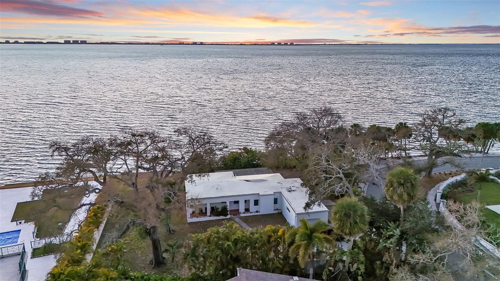 A rare chance to own a prime bayfront property in Sarasota’s highly desirable Sapphire Shores / Indian Beach neighborhood. Positioned on a 0.51-acre lot with 136 feet of direct Sarasota Bay frontage, 820 Indian Beach combines unobstructed water views, a generous homesite, and a location that continues to grow in demand. The property is currently an income producing rental property. The existing residence reflects a classic mid-century modern style, defined by clean architectural lines, a bright white exterior, vaulted ceilings, and large picture windows that bring in consistent natural light. The interiors are open and airy, with living spaces oriented toward the backyard and bay, creating a comfortable, relaxed atmosphere throughout the home. The outdoor setting is a standout feature. The bayfront positioning provides wide water views, while mature trees and the depth of the lot offer privacy and shade. A pergola and expansive patio create functional outdoor living areas, and a private path leads directly toward the water. Riprap spans the bayfront perimeter, securing the shoreline. Inside, the home offers three bedrooms and three bathrooms across 1,915 square feet under air. Wood flooring, abundant windows, and simple, clean finishes maintain a cohesive aesthetic. The kitchen and breakfast area are bright and practical, with large windows overlooking the backyard and water. Beyond the home itself, the true value of 820 Indian Beach Road is the land. Bayfront lots with this amount of frontage and lot size are increasingly limited within Sapphire Shores / Indian Beach, making the property an excellent candidate for a renovation, expansion, or entirely new construction. The homesite provides the scale and orientation to support a significant custom residence designed to maximize the views. The neighborhood remains one of Sarasota’s most established waterfront areas, known for its tree-lined streets, varied architecture, and close proximity to downtown Sarasota, St. Armand's Circle, shopping, dining, and Sarasota-Bradenton International Airport. 820 Indian Beach Road represents both an immediate waterfront lifestyle opportunity or investment and a highly compelling long-term property in a consistently sought-after location.