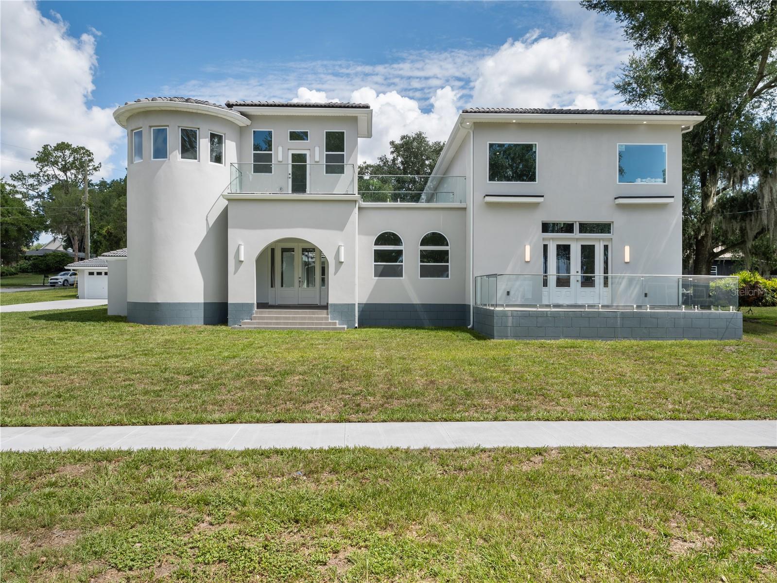 Stunning Remodeled Home with Lake Views in Clermont's Desirable Indian Hills Community
Discover this one-of-a-kind residence in the highly sought-after Indian Hills community, just minutes from downtown Clermont. Enjoy convenient access to waterfront parks, shopping, dining, entertainment, and year-round community events while taking in charming views of Lake Minnehaha.
A grand entry welcomes you into an impressive foyer that opens to an expansive living and dining area featuring soaring 20-foot ceilings and a striking LED fireplace that provides both supplemental heat and customizable ambiance. The living room extends to a spacious balcony overlooking the lake, creating the perfect setting for entertaining, relaxing, and enjoying Clermont's renowned sunsets.
This exceptional property has been extensively transformed, with more than 3,500 square feet added through new construction beyond the original home, creating a unique and spacious floor plan rarely found in the area. Completely remodeled throughout, the residence showcases premium finishes, designer touches, luxury flooring, and beautifully renovated bathrooms, delivering a sophisticated yet comfortable living experience.
Designed with flexibility in mind, the home features two spacious primary suites. One suite includes an attached loft ideal for a home office, reading nook, or creative space, while the second offers a private den that can serve as an office, fitness room, or sitting area. Both suites feature oversized closets and generously sized bathrooms, creating luxurious private retreats.
Two additional bedrooms provide comfortable accommodations for family and guests and include customized closet systems for enhanced organization and storage.
The beautifully updated kitchen is designed for both everyday living and entertaining, featuring a large center island, abundant counter space, a massive walk-in pantry, all-new appliances, and a double oven. Adjacent to the kitchen is a versatile bonus space offering endless possibilities, including the potential for a future elevator providing direct access to the primary suite, a temperature-controlled wine storage area, a custom humidor, or additional specialty storage tailored to your lifestyle.
Step outside to your private courtyard oasis, complete with oversized tile pavers and low-maintenance artificial turf—an ideal space for outdoor dining, entertaining, or simply enjoying Florida's year-round lifestyle.
Additional features include:
Two new high-efficiency A/C systems
All-new appliances
Double oven
Spacious two-car garage with attached workshop
Dedicated office retreat accessed by a dramatic spiral staircase
Private office balcony with elevated views
New Tankless water heater
With its distinctive floor plan, substantial new construction, extensive renovations, modern upgrades, private outdoor spaces, and desirable location near downtown Clermont, this turnkey home offers a rare opportunity to enjoy luxury, flexibility, and Florida living at its finest.