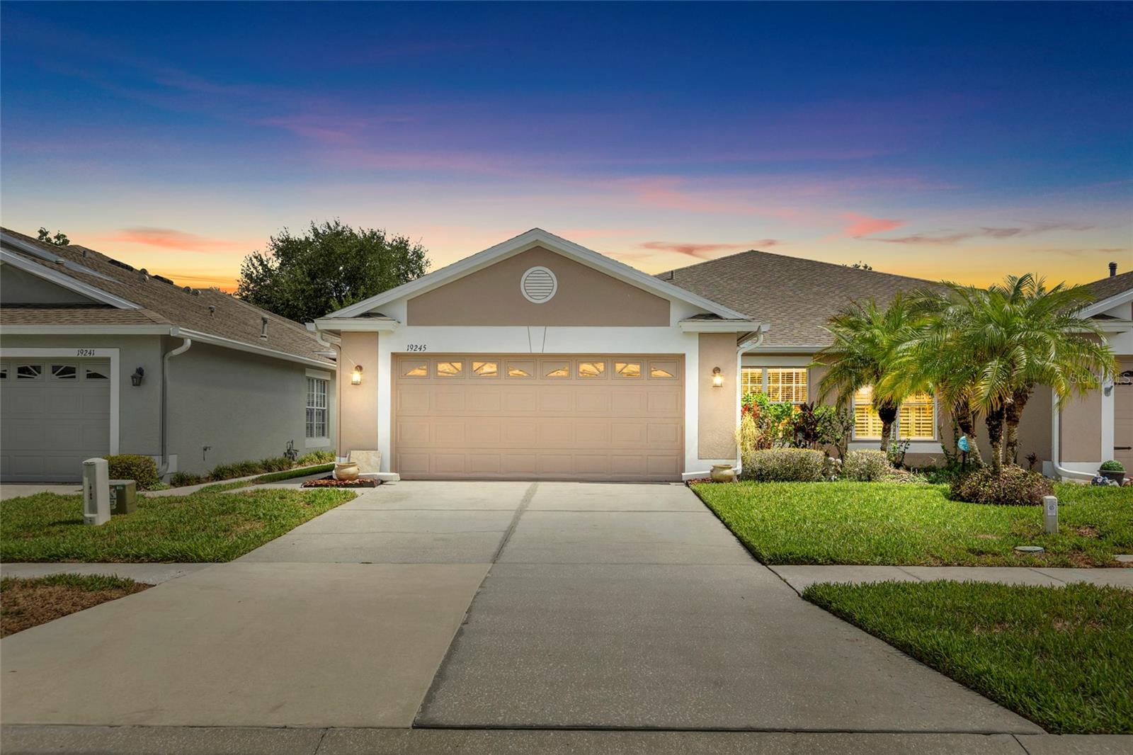One or more photo(s) has been virtually staged. Welcome to maintenance-free living in the highly desirable gated community of Tanglewylde Village at Oakstead! This beautifully maintained 2-bedroom, 2-bath villa with a dedicated den offers 1,661 square feet of thoughtfully designed living space. Inside, you’ll find elegant tile flooring throughout the main living areas and rich hardwood flooring in select rooms, creating a warm and inviting atmosphere. The open-concept floor plan flows seamlessly from the spacious living and dining areas into the well-appointed kitchen, featuring abundant cabinet storage, pull-out shelving, a gas range (more affordable), dishwasher, microwave, modern refrigerator, and a bright breakfast nook. Large windows fill the home with natural light while offering peaceful views of the surrounding greenery.  The versatile den provides the perfect space for a home office, hobby room, or potential third bedroom. The split-bedroom layout ensures privacy for both owners and guests. The spacious primary suite is a true retreat, featuring updated ceramic flooring, dual oversized walk-in closets with custom wood organizers and hidden safe, elegant glass closet doors, and a hidden built-in safe. The en-suite bath offers a garden tub, separate updated walk-in shower with glass enclosure, dual sinks, and a large updated vanity. Both bathrooms feature ceramic tile walls and flooring along with updated glass shower doors.  Additional highlights include a 2-car garage, gas heating for enhanced energy efficiency, a newer water heater, and low-maintenance living with exterior upkeep handled by the HOA. Residents enjoy access to Oakstead’s exceptional amenities, including a clubhouse, resort-style pool, fitness center, tennis courts, playgrounds, and scenic walking trails. The HOA also covers lawn maintenance, tree trimming, exterior painting, and roof replacement, providing true peace of mind.  Conveniently located near top-rated schools, shopping, dining, medical facilities, and major highways, this move-in-ready home offers easy access to everything Wesley Chapel and the Tampa Bay area have to offer. Florida living at its best!