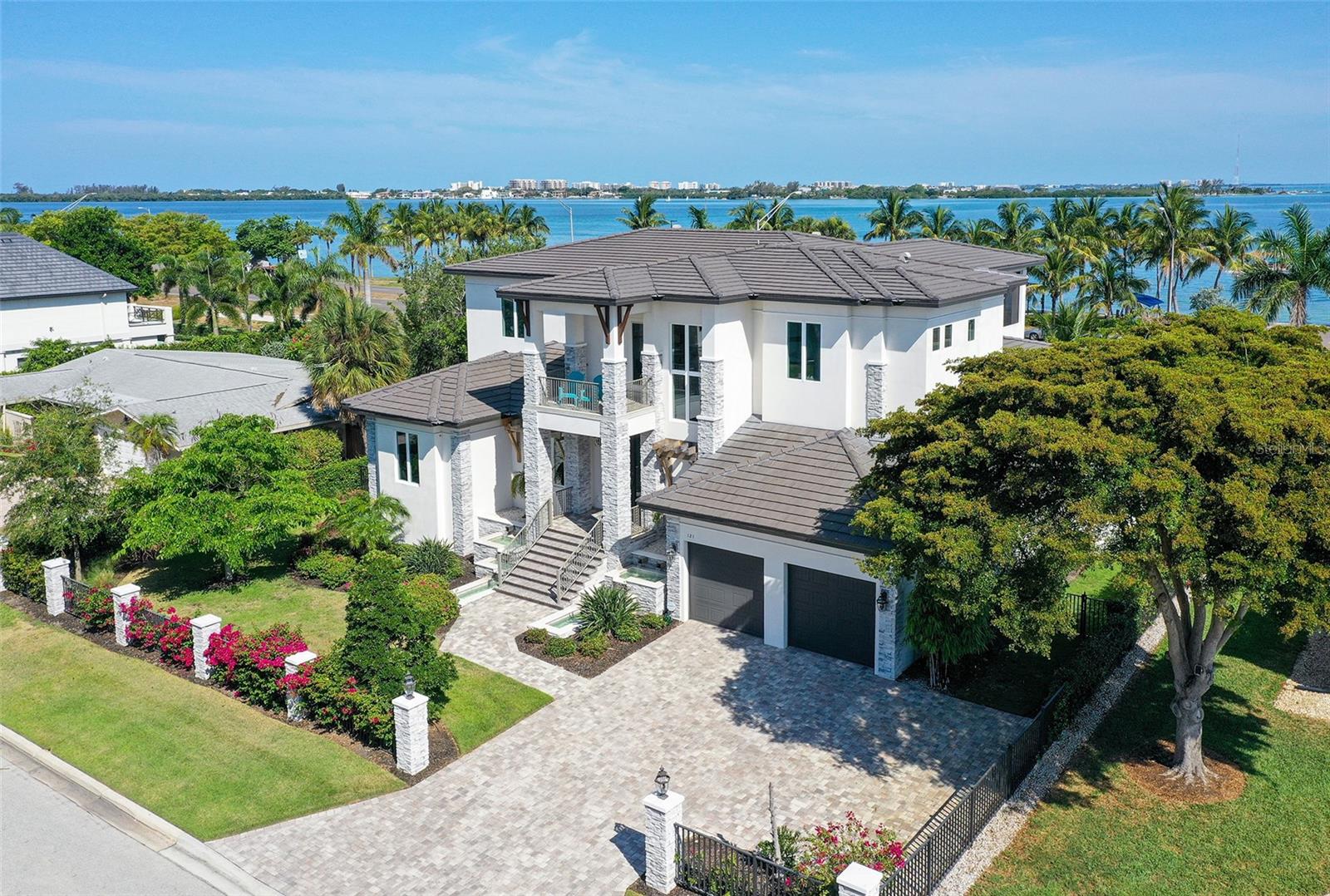 Luxurious Living Redefined on Bird Key! Welcome to the epitome of modern elegance! Step into this custom-designed "smart home" by John Cannon Homes, where beauty, simplicity, and sophistication converge to offer you the ultimate lifestyle experience. As you approach, be greeted by a mesmerizing cascading waterfall feature and enter through grand custom glass double doors into a marble foyer adorned with a contemporary chandelier. Towering 11'4" ceilings adorned with custom crown moldings guide you through the sleek marble floors of the first floor, leading seamlessly to an outdoor oasis boasting breathtaking views of Sarasota Bay. Indulge your culinary desires in the gourmet kitchen, equipped with top-of-the-line Viking appliances including a 48" Tuscany Range and a spacious quartz island perfect for family breakfasts or entertaining guests. Transition effortlessly to the expansive outdoor living space featuring two covered balconies, a two-story enclosed pool, and a fully equipped outdoor kitchen ideal for al fresco dining. This home is designed for relaxation and entertainment with spacious guest rooms offering tranquil retreats flooded with natural light. Upstairs, discover a second-floor great room with hardwood floors, wet bar, and balcony access, offering panoramic views of the bay and heated lap pool below. Unwind in the luxurious master suite featuring a personal spa area with a Kohler soaking tub, custom-tiled shower, and ample walk-in closets. With a second bedroom boasting an ensuite bathroom and balcony access, every corner of this home exudes comfort and style. Embrace the future with this technologically advanced smart home, granting you control of lighting, music, security, and more directly from your phone, no matter where you are in the world. Conveniently located just moments from St. Armand's Circle and Downtown Sarasota, indulge in the vibrant arts scene, epicurean delights, and pristine beaches that define life on Bird Key. Don't miss your chance to elevate your lifestyle and start living your best life in paradise. Schedule your private tour today and experience modern living redefined!