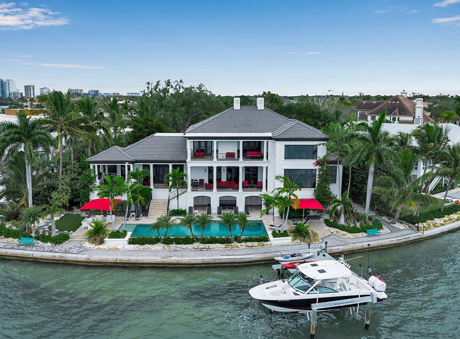 Set within the prestigious Harbor Acres neighborhood—one of Sarasota’s most sought-after waterfront enclaves, this stunningly renovated gated estate occupies an exceptional lot on the Hillview Point with 171 feet of Sarasota Bay frontage and sweeping, unobstructed panoramic views. This magnificent two-story residence, designed by renowned architect Cliff Scholz, offers six bedrooms, seven full baths, and two half baths, complemented by an oversized three-car garage—providing a seamless blend of architectural grandeur and everyday livability. A dramatic two-story foyer welcomes you inside, where expansive west-facing walls of glass capture breathtaking water vistas and bathe the home in natural light. The main level is thoughtfully designed for both refined entertaining and comfortable living, featuring a waterfront living room, an inviting family room, and an elegant dining room. At the heart of the home, the gourmet kitchen showcases authentic zebrawood cabinetry celebrated for its exotic grain patterns and rich natural character, paired with Quartz countertops, a generous center island, premium appliances, and a breakfast area with a dedicated coffee bar—perfectly suited for intimate mornings or hosting on a grand scale. Additional highlights include a private library, executive office, a full-service bar, and secondary laundry room. The owner’s suite is a serene waterfront sanctuary, offering tranquil Sarasota Bay views, dual spa-inspired bathrooms, three walk-in closets, and a private laundry—creating a truly elevated retreat experience. Ascend the sweeping staircase or take the private elevator to the second level, where five beautifully appointed guest suites provide exceptional comfort and privacy. Two of these suites, along with the upstairs library, enjoy coveted waterfront positioning and direct access to a spectacular 35-foot terrace overlooking Sarasota Bay—an ideal setting for morning coffee, sunset cocktails, or quiet moments of reflection. An additional laundry room on this level adds to the home’s thoughtful functionality. Outdoor living is equally impressive. Host unforgettable gatherings on the expansive 76-foot elevated terrace with summer kitchen or unwind poolside at the resort-style terrace featuring a 55-foot heated pool and generous lounging areas. For boating enthusiasts, private dockage delivers effortless access to Sarasota Bay and the open waters beyond. This extraordinary waterfront estate embodies the very essence of Sarasota luxury—where timeless design, exceptional craftsmanship, and unparalleled coastal views come together in a truly rare offering.