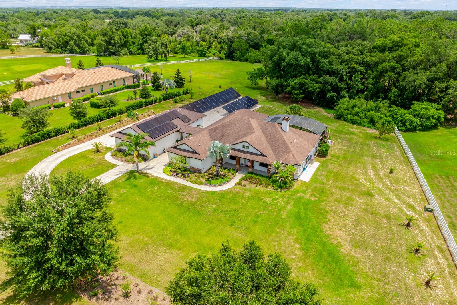 CANAL FRONT with ACCESS TO THE HARRIS CHAIN OF LAKES, Set on 2.32 PICTURESQUE ACRES inside the GATED ~ EQUESTRIAN COMMUNITY of Beauclair Ranch Club, this CUSTOM BUILT ~ 6-bedroom / 4-bath ~ POOL HOME with a 4-car detached garage offers the perfect blend of privacy, luxury, and energy-efficient living! Major updates lead the way, including ***FULLY OWNED SOLAR PANELS that are currently providing COMPLETE ENERGY COVERAGE*** – often producing a monthly surplus, a BRAND NEW COOKTOP (2026), EXTERIOR PAINT (2023), and septic service completed in (2023). A 210 ft well and double-pane windows add to the home’s long-term efficiency and peace of mind. From the moment you arrive, the property’s expansive setting and scenic views create an impressive first impression. The home’s detached 4-car garage with workshop space is connected by a covered walkway, offering plenty of room for vehicles, hobbies, storage, or recreational equipment. The original 3-car garage has been thoughtfully converted into a spacious sixth bedroom with a full bath, making it an ideal IN-LAW SUITE, guest retreat, or private living quarters. Inside, elevated design details are found everywhere you turn, including CROWN MOLDING throughout, ENGINEERED HARDWOOD flooring in the main living areas, and a light, bright OPEN CONCEPT layout designed for both everyday living and entertaining. The 3-WAY SPLIT BEDROOM floor plan provides excellent separation of space, and nearly every bedroom features walk-in closets. The home offers a variety of functional spaces including a FORMAL DINING room, a dedicated OFFICE with a built-in desk, and a convenient MUDROOM/laundry room. At the center of it all is the gorgeous chef’s kitchen, designed to impress with an OVERSIZED ISLAND offering seating on both sides, granite countertops, rich cabinetry, decorative backsplash, STAINLESS STEEL APPLIANCES, beverage refrigerator, and the brand new cooktop with a custom range hood that seamlessly matches the cabinetry. The kitchen flows effortlessly into the light filled casual dining space and the spacious living room, making it an entertainer’s dream! The living room features a timeless stacked-stone WOOD BURNING FIREPLACE and TRIPLE SLIDING GLASS DOORS that open wide to the COVERED LANAI and SCREENED POOL & SPA, creating the ultimate INDOOR/OUTDOOR Florida lifestyle. The PRIMARY SUITE is privately positioned away from the other bedrooms, offering a peaceful retreat with a decorative tray ceiling, abundant natural light, direct access to the lanai and pool, a sitting area, DUAL WALK-IN CLOSETS, and a well-appointed en-suite bath featuring dual sinks and a massive CUSTOM WALK-IN SHOWER. Outside, the sprawling property provides beautiful open views, privacy, and room to breathe, all within the sought-after Beauclair Ranch Club, a gated equestrian community known for its spacious homesites and serene setting. Despite the peaceful acreage lifestyle, you are just off SR 448 with quick access to US-441, making it easy to reach shopping, dining, and daily conveniences throughout Mount Dora, Tavares, and the surrounding Lake County area. With fully owned solar, a flexible multi-generational layout, resort-style pool living, and acreage inside a gated equestrian community (bring your horses!), this exceptional property truly offers everything you could want in a home. Some furnishings are negotiable, making it even easier to move right in and start enjoying the lifestyle. Call today to schedule a tour!