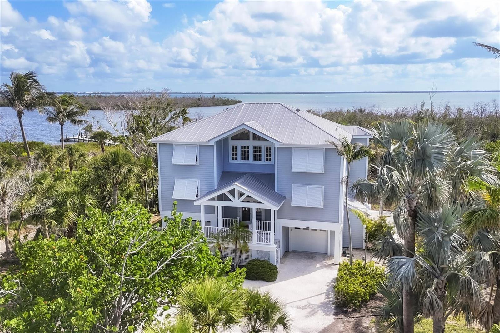 Located on Gasparilla Island beyond a private driveway, this one-of-a-kind retreat spans generous acreage and captures panoramic bay and coastal water views. Positioned on 1.88 acres and framed by native landscaping, the serene setting feels worlds away, yet remains just minutes from the charm of Boca Grande village.
Spanning 2,951 square feet of refined living space with a total footprint of 6,287 square feet, the residence features three bedrooms plus a study or bonus room that can easily serve as a fourth bedroom, along with three-and-a-half baths. An interior elevator services all floors, ensuring effortless access throughout. The interiors reflect a sophisticated coastal aesthetic, highlighted by light-colored hardwood floors and thoughtfully designed living spaces.
The study features a wet bar, opens to an exterior porch, and offers a perfect spot for stargazing, while the upstairs primary suite enjoys its own private porch—both providing sweeping Bay views and front-row seats to abundant wildlife, including osprey, pelicans, and egrets. An expansive porch running the length of the home invites morning coffee with sunrises over the water and evenings bathed in soft sunset hues. Electric hurricane shutters provide peace of mind, while the three-car, climate-controlled garage plus dedicated golf cart space adds everyday convenience.
Leisurely bike rides or golf cart trips along the paved path lead directly into the village of Boca Grande, known for exceptional dining, unique shopping, world-class fishing, and outstanding boating. Properties of this size, setting, and water-view presence are exceptionally rare on the island, making this a truly special opportunity.