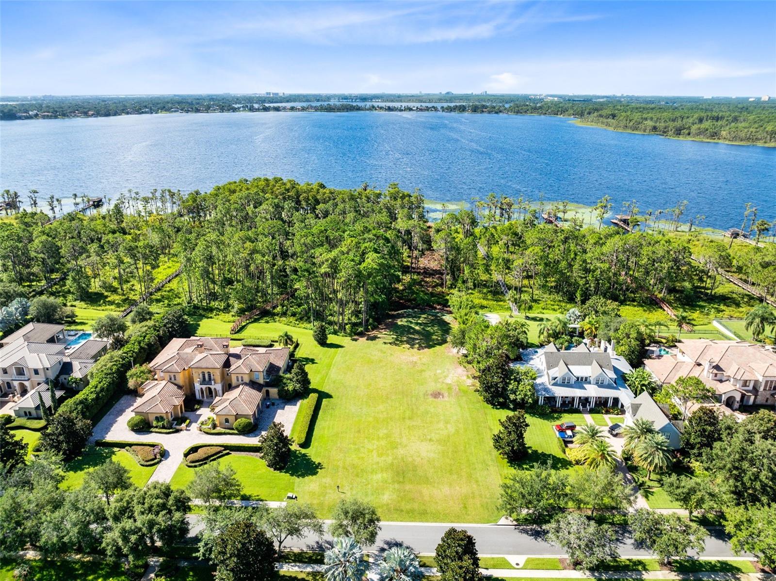 Positioned on over two acres with an impressive 136 feet of pristine shoreline on the Butler Chain of Lakes, this exceptional homesite offers an increasingly rare chance to craft a custom lakefront estate in one of Windermere’s most exclusive gated communities. Set within a distinguished enclave of Keene’s Pointe—surrounded by multi-million-dollar residences and mature landscaping—this property captures sweeping views of shimmering Lake Tibet, part of the renowned 13-lake Butler Chain.
One of the final remaining lakefront lots in the community, the site features a wide, level building pad with utilities conveniently located at the property line. A conservation easement enhances the privacy and natural beauty of the setting, while deeded lake access opens the door to an enviable waterfront lifestyle—boating, paddleboarding, and stunning sunset vistas, right from your backyard.
Buyers may select from Keene’s Pointe’s roster of approved luxury builders to design and construct a custom residence tailored to their vision. Imagine constructing your dream and leaving a legacy for future generations. As a resident, enjoy the option to join the Golden Bear Club, with access to a private Jack Nicklaus Signature golf course, tennis, pickleball, resort-style pool, state-of-the-art fitness center, clubhouse dining, and a vibrant calendar of social events.
This is more than a lot—it’s an opportunity to build your dream home on one of Central Florida’s most prestigious lakes. Luxury lakefront living awaits.
