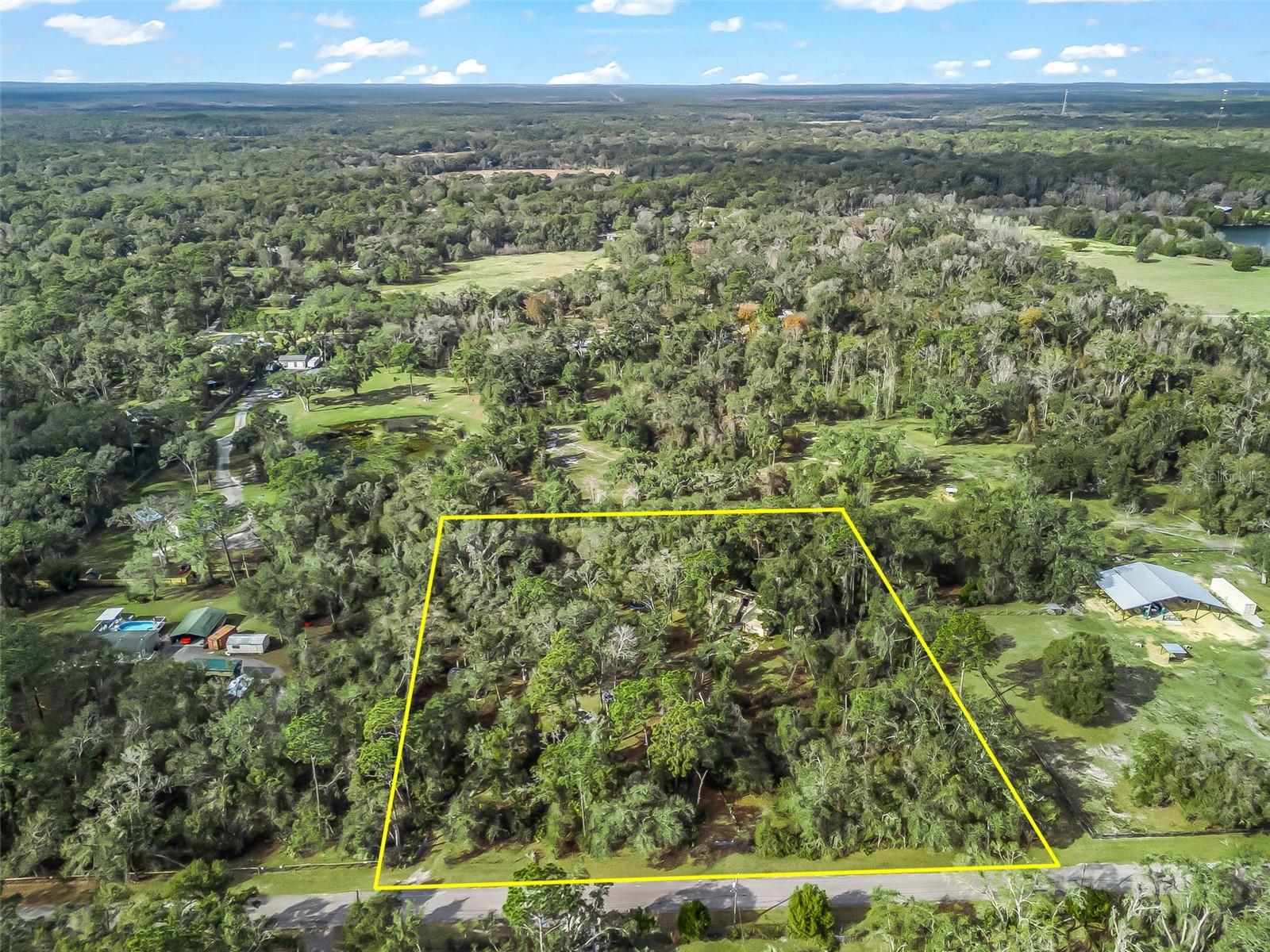 NEW PRICE on this tucked-away residence on 2.5+/- wooded acres, offering a rare blend of privacy, character, and creative potential. Surrounded by nature, the 2-bedroom, 2-bath block home is thoughtfully designed to blend seamlessly with its serene setting while providing a compelling foundation for refined customization. A dramatic spiral staircase serves as a sculptural focal point, ascending to a light-filled bonus retreat wrapped in rich cedar wood walls. An adaptable space well-suited for a home office, creative studio, entertaining lounge, or additional bedroom. Throughout the home, cedar wood ceilings add warmth and continuity, complemented by brand-new carpeting, while a striking stone fireplace anchors the main living space. Multiple sliding glass doors extend the interiors outward to patios and nature's tranquil views, creating seamless indoor-outdoor living and entertaining opportunities. The primary suite functions as a private sanctuary, complete with its own bath and direct patio access. The unfinished patio and elevated entertaining area present an exceptional opportunity to further enhance and personalize the outdoor living experience. The grounds reinforce the home’s retreat-like atmosphere, featuring a koi pond with a charming bridge, a fire pit, winding walking trails, including a concrete slab ideal for a future garage or workshop, along with a separate 10x20 storage building. Secluded, distinctive, and rich with potential, this one-of-a-kind property is ideal for those seeking a private woodland escape with the flexibility to craft a truly customized lifestyle. Perfectly balancing privacy with accessibility, it is conveniently located with easy access to I-75, U.S. Hwy 301, and State Road 50, offering a manageable commute to Ocala, Tampa, and Orlando. Just minutes from the Webster Flea Market, Sumter County Fairgrounds, and local shopping and dining. Outdoor recreation abounds with nearby lakes, nature trails, and the Withlacoochee State Forest. Enjoy the best of Florida living with Gulf Coast beaches and natural springs, approximately 45 minutes to one hour away. A rare offering where privacy, natural beauty, and architectural distinction converge is best appreciated through a private showing.