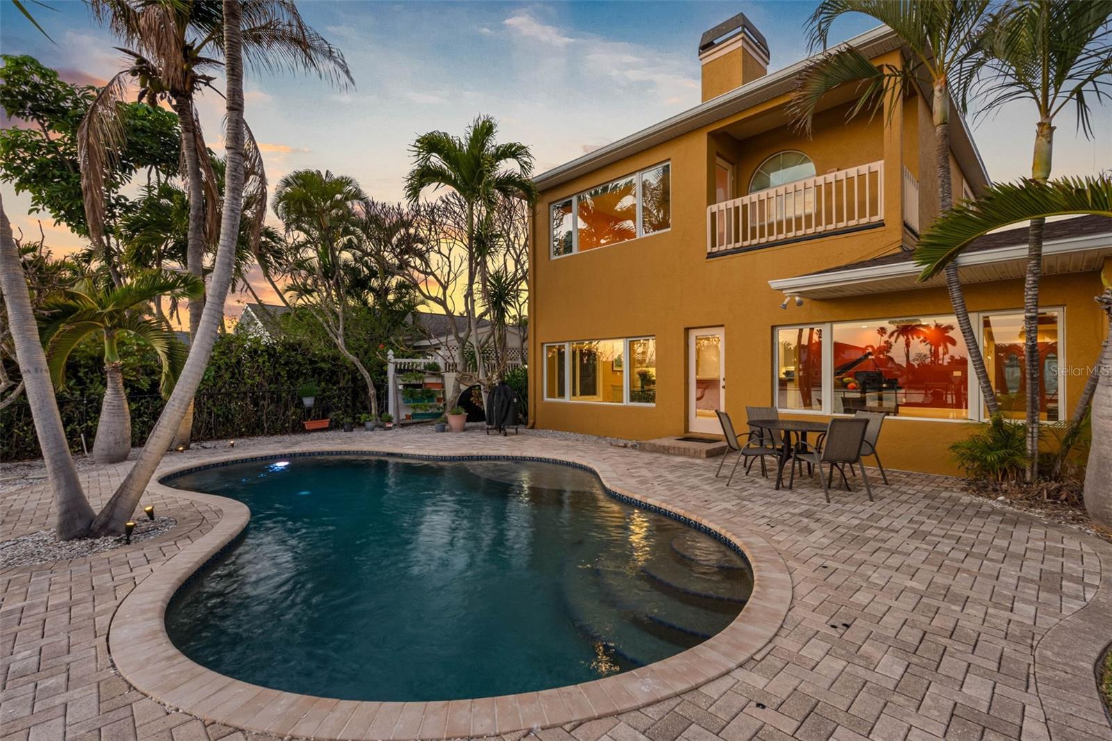Experience the ultimate in coastal living with this stunning waterfront pool home, perfectly situated on the highly sought-after Isle of Palms in Treasure Island. Boasting over 2,700 square feet of beautifully designed open-concept living space, this residence is tailor-made for both relaxed everyday living and unforgettable entertaining. The heart of the home is a completely updated kitchen featuring all-new cabinetry, stainless steel appliances, and expansive granite countertops—ideal for hosting gatherings with ease. Modern upgrades abound, including new HVAC, water heater, and updated wiring, while Caseta smart lighting allows you to control ambiance both indoors and out with the touch of a button. On the main level, you’ll find two spacious bedrooms, including one with an ensuite bath and serene views of the pool and waterfront. A second full bath, also finished with granite countertops, provides convenience for guests and family alike. Upstairs, the private primary suite offers a true retreat. This expansive space includes a second adjoining room—perfect for a home office, nursery, or additional bedroom—along with an oversized bathroom featuring a two-sided wood-burning fireplace that creates a warm, luxurious atmosphere in both the bedroom and bath. A wet bar, walk-in closet, and private balcony overlooking the PebbleTec pool and tranquil water views complete this exceptional suite.
Step outside to your personal waterfront oasis. The PebbleTec pool sparkles under the Florida sun, while the composite dock with a spacious seating area invites you to unwind with evening “docktails” as you take in breathtaking, technicolor sunsets. Located just moments from Treasure Island’s award-winning beaches, this home places you in the heart of a vibrant coastal community known for its lively festivals, including the world-renowned sand sculpting competition. Enjoy charming local shops, waterfront dining, and fresh-caught seafood delivered straight from the boats. This is more than a home—it’s a lifestyle.