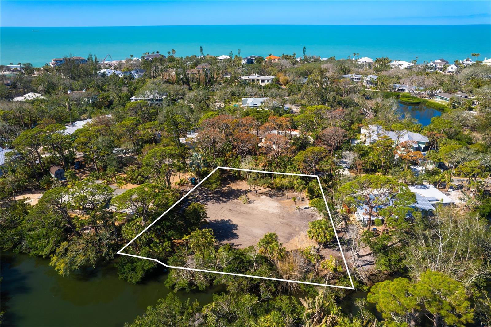 Tucked beneath a canopy of mature trees in the prestigious Sanderling Club, this exceptional waterfront homesite presents a rare opportunity to own in one of Siesta Key's most established and coveted Gulf-front communities. Encompassing more than half an acre, the property offers 152 feet of frontage on tranquil Heron Lagoon, creating a peaceful natural setting for kayaking, paddleboarding, canoeing, fishing and enjoying Florida's coastal wildlife from your own backyard. The Sanderling Club is Siesta Key's original guard-gated community, renowned for its privacy, natural beauty, large homesites and timeless Old Florida character. Residents enjoy exclusive access to a private Gulf-front beach, where uncrowded, spectacular sunsets become part of everyday life. A distinctive feature of the community is its resident marina, where boat slips may be rented by homeowners, providing direct access to Sarasota Bay, the Intracoastal Waterway and the Gulf of Mexico. It is an increasingly rare convenience that allows residents to enjoy an active boating lifestyle without the expense and maintenance of private dock ownership. The Sanderling Club is also entering an exciting new chapter, with thoughtfully reimagined community gathering spaces designed to create even more opportunities for neighbors and friends to connect while preserving the beauty, character and sense of place that have long defined this treasured neighborhood. Just beyond the gates, residents enjoy easy access to the world-renowned quartz sands of Siesta Beach, the boutiques and restaurants of Siesta Village and the vibrant arts and cultural attractions of downtown Sarasota, including theater, opera, ballet, galleries and museums. One of the few remaining opportunities to create a custom waterfront residence in this remarkable community, this homesite offers the setting, privacy and lifestyle that are increasingly difficult to find on Siesta Key. Offered by a motivated seller, this is an exceptional opportunity to secure your place in one of Sarasota's most treasured coastal communities.