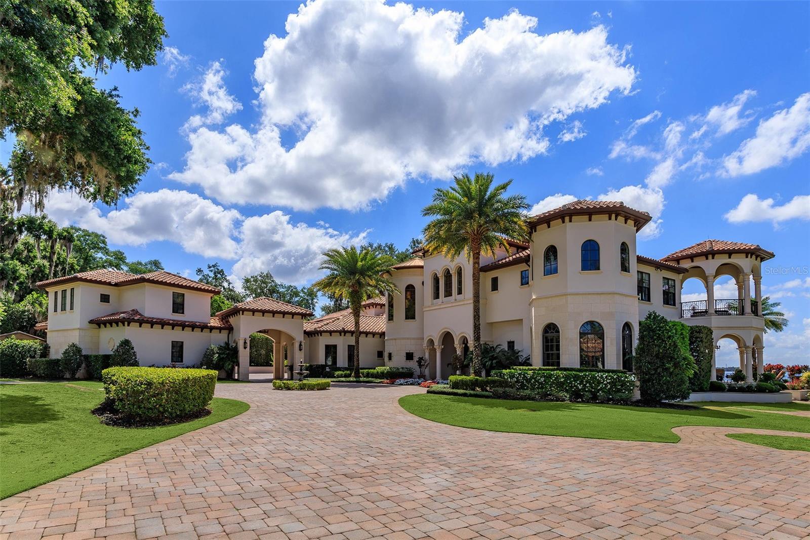 Presenting Sunset Isle: an iconic waterfront estate compound capturing timeless elegance on Windermere’s largest and most prestigious Lake Butler, offering captivating unobstructed views from its 700 feet of lake frontage, a private island with moat and drawbridge, sandy beaches, two story double residence guest house, and a majestic and stunning grand mansion with additional guest retreat, all spanning more than 14,444 square feet of living space and 11 bedrooms across both residences. Welcome to this one-of-a-kind haven of privacy and prominence showcasing the best of Central Florida living. Set on a rare 3.75 acres commanding enviable views on the northern shore of Lake Butler, every detail has been thoughtfully designed to celebrate both refinement and tranquility. The impressive palatial main residence boasts 10,649 square feet of living space with 6 bedrooms plus a one-bedroom guest retreat and an array of curated spaces. The Spanish Eclectic interior fuses classic craftsmanship with modern sophistication, creating an inviting and awe-inspiring escape from the ordinary. On entrance be greeted by sweeping floor to ceiling windows to allow breathtaking water vistas, double-sided gas fireplace, a grand colonnade hallway, and architectural details throughout. The gourmet chef’s kitchen features top of the line appliances, gas range with multiple burners, ovens, island with second sink, and walk-in pantry. A sports bar games room and showstopping home theater provide an abundance of entertaining options. Other notable amenities include a Castilian wine cellar, bay windows, two wet bars, private salon, elevator, gym, steam room and sauna. Outdoors, a generous summer kitchen with automatic roller screens provide an outdoor oasis for al fresco dining, cooking, or relaxing. The zero-entry infinity pool and vast resort decking provide a breathtaking vantage point for panoramic views of Lake Butler’s radiant sunsets, while the shaded Zen garden and white sandy beach offer a tranquil retreat for quiet reflection. With many distinct outdoor venues, serenity is never far away. The estate’s private island, accessed by an electric drawbridge, and a boat ramp provide unmatched exclusivity to Lake Butler and the world-famous Butler Chain of Lakes. The two-story detached guest house offers 3,795 sq feet of living space across two, 2-bedroom apartment homes, each with kitchens, laundry rooms, an elevator, and attached two-car garage. Built for a large multi-generational family, guest quarters, or on-site caretakers, the possibilities are endless. Truly a picture-perfect unmistakable showplace offering the very best for the most discriminating buyer.