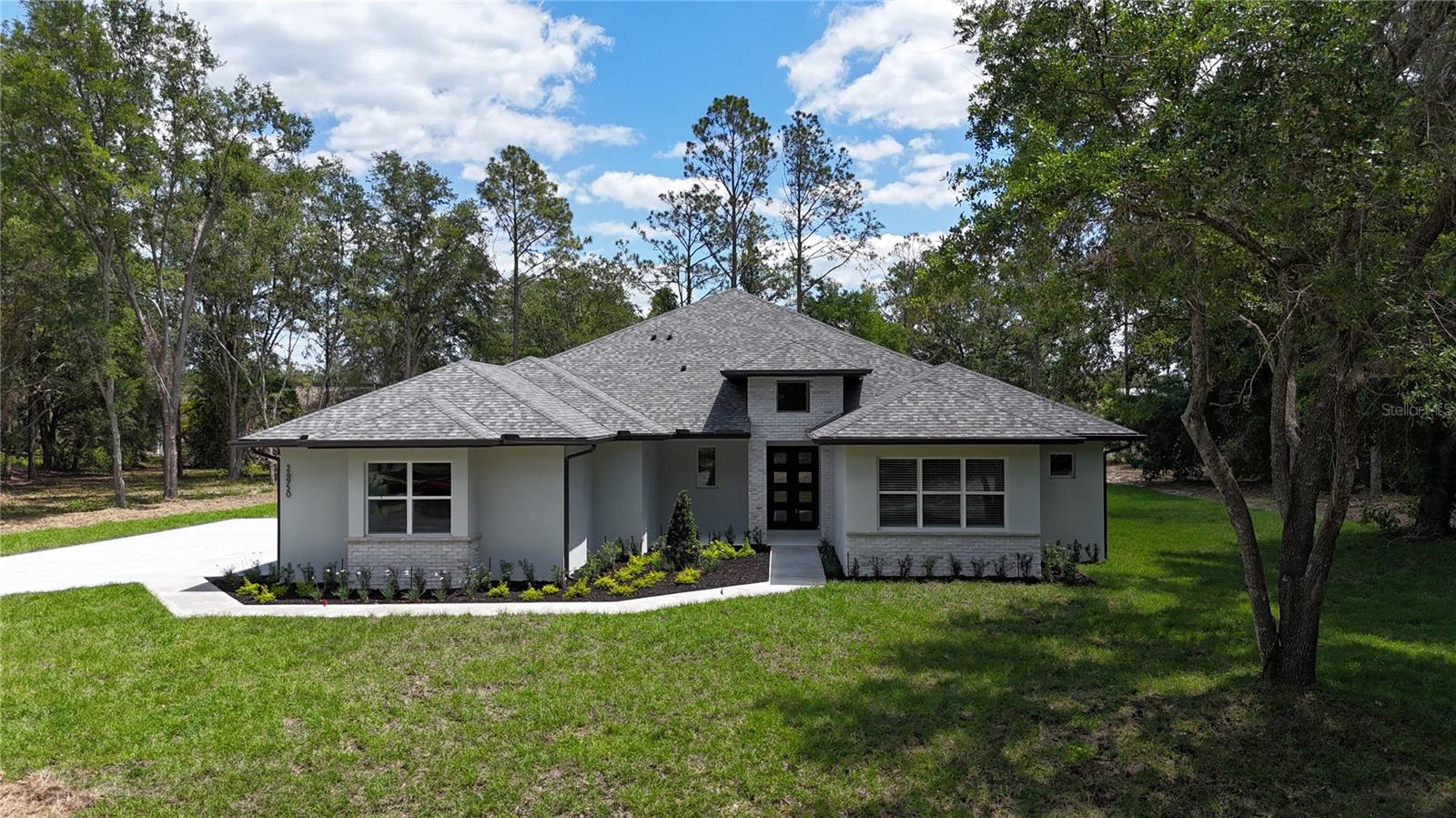 Discover elevated living in this stunning new construction home located at 24950 Bonsmara Dr in Groveland, FL. Nestled on an expansive 1.05-acre lot within a peaceful gated community, this 4-bedroom, 3.5-bath residence offers the perfect blend of luxury, comfort, and modern design.

Step inside to an inviting open floor plan featuring soaring 10-foot ceilings, LED lighting, and elegant finishes throughout. The spacious living area flows seamlessly into a chef-inspired kitchen complete with quartz countertops, marble backsplash, stainless steel appliances, a large island, walk-in pantry with outlets, and a wine/beverage fridge—perfect for entertaining. A cozy breakfast nook and formal dining room with double French doors open to a charming breakfast porch, bringing in natural light and serene outdoor views.

The luxurious primary suite is a private retreat, boasting a spa-like ensuite bath with dual vanities, a soaking tub, and a spacious walk-in shower. Dual custom walk-in closets—including a reinforced safe room—add both style and security. Additional bedrooms are generously sized, and a flexible 4th room can serve as a home office, study, or library.

Designed for both indoor and outdoor living, the home features a covered patio prepped for an outdoor kitchen, a welcoming front porch, professional landscaping, irrigation system, and ambient outdoor lighting. The 3-car garage, mudroom, and a well-appointed laundry room with built-in cabinetry add everyday convenience.

Premium upgrades include rigid core luxury vinyl flooring, spray foam insulation for energy efficiency, a 200-amp transfer switch, water softener with sulfur filtration system, and a custom handcrafted iron front door that makes a bold first impression.

Located in an exclusive 87-lot gated community, residents enjoy access to amenities such as a tennis court, pickleball, and a scenic fishing dock on Clearwater Lake. Conveniently close to local schools, yet surrounded by nature and wildlife, this home offers the best of both privacy and accessibility.

With over 3,100 sq ft of living space and nearly 4,700 total sq ft, this exceptional property delivers luxury living at its finest.