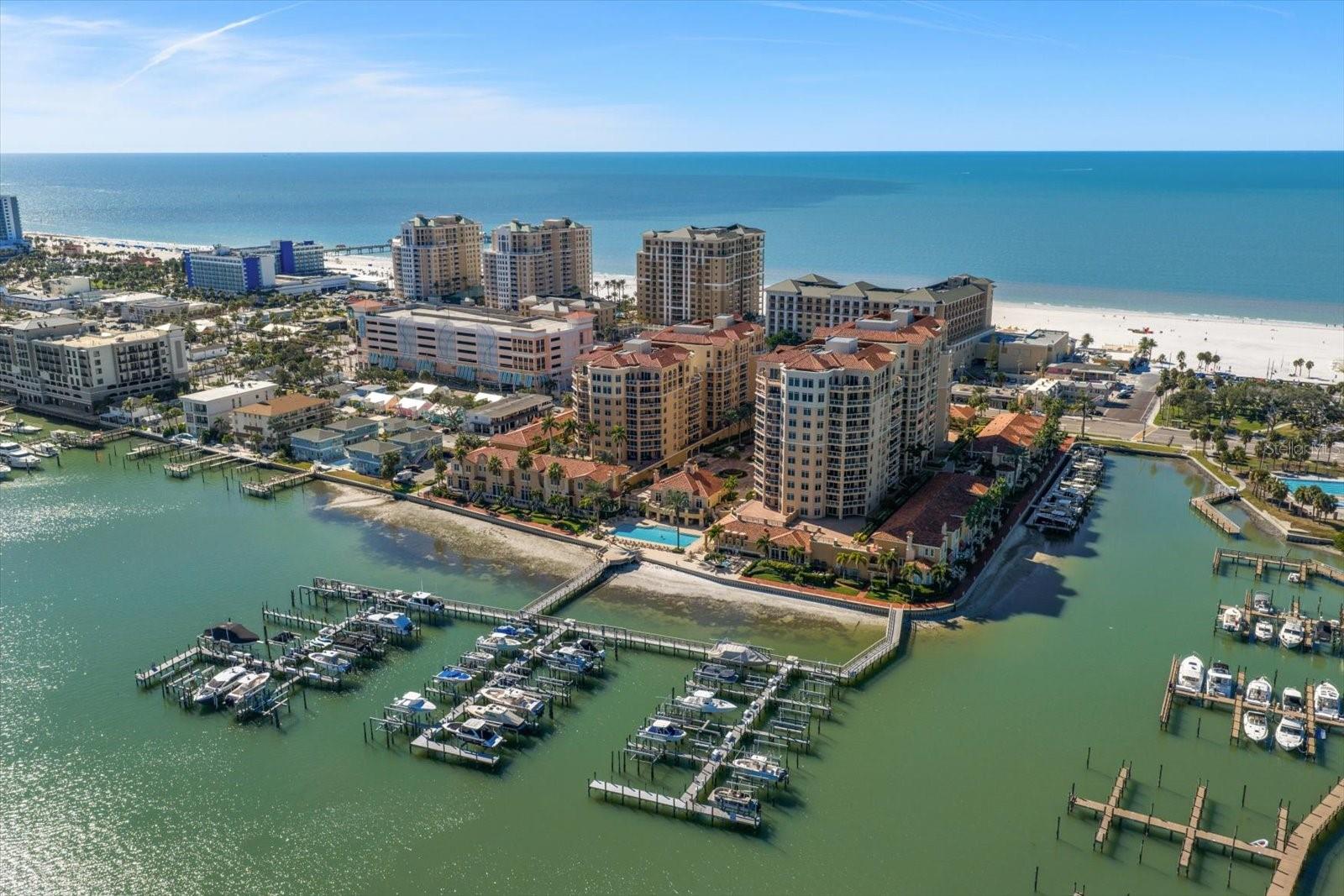 The finest of coastal luxury unfolds at Belle Harbor, where sweeping Gulf views and mesmerizing sunsets create an ever-changing backdrop to celebrate everyday life. Perfectly positioned along the pristine shores of Clearwater Beach, this exceptional residence offers a front-row seat to paradise. An inviting light-filled interior boasts refined design and elevated finishes, with walls of windows and multiple terraces. A light and bright chef’s kitchen features custom finishes and stainless steel appliances, a welcoming breakfast bar, and a dining area that flows seamlessly into the great room. Expansive sliders guide you to the gracious covered balcony that captures breathtaking vistas and offers the perfect setting for morning coffee or a sunset cocktail. A luxurious primary suite delivers a private sanctuary, designed for comfort and tranquil escape. Featuring terrace access, wake to panoramic Gulf views, unwind in a spa-inspired bath complete with a glass-enclosed shower, deep soaking tub, and a generous custom walk-in closet. Additional features include plantation shutters,  abundant storage, a spacious laundry room, and the convenience of being offered partially furnished. Experience the best of coastal living in Belle Harbor’s secure, pet-friendly community. Offering 6.5 acres of prime waterfront and a true island escape with an impressive collection of resort-style amenities. Residents enjoy 24-hour gated security, clubhouse, state-of-the-art fitness center, heated pool and spa, sauna, club rooms, on-site management, assigned parking, additional storage, and private dockage. Moments away, the vibrant energy of Clearwater Beach awaits—renowned for its sugar sands, refined dining, boutique shopping, and the lively atmosphere of Pier 60 with year-round events and sunset celebrations. Have the best of Florida Coastal Luxury Lifestyles on world-famous Clearwater Beach.