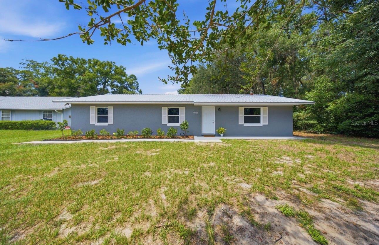 Virtually Staged. Better Than New – Fully Updated 3 Bedroom, 2 Bath Home in Lake Weir Gardens! Nestled in the established community of Lake Weir Gardens, this beautifully updated concrete block home offers the perfect blend of modern upgrades, quality construction, and a peaceful rural atmosphere—all while remaining conveniently close to shopping, restaurants, medical facilities, and everyday necessities.  This 3-bedroom, 2-bath home offers over 1,500 square feet of comfortable living space and has undergone extensive improvements, making it truly move-in ready. From the moment you arrive, you’ll appreciate the freshly landscaped grounds, newly painted exterior completed in 2026, and durable metal roof installed in 2021, creating exceptional curb appeal and a welcoming first impression. Step inside to discover a bright and inviting interior featuring luxury plank flooring throughout and an open-concept layout designed for today’s lifestyle. The beautifully renovated kitchen, updated in 2020, serves as the heart of the home with butcher block countertops, a stylish tile backsplash, stainless steel appliances, and a new dishwasher installed in 2026. The open design allows for effortless entertaining while keeping family and guests connected. Recent improvements include:
* Metal roof (2021)
* Complete interior and exterior paint (2026)
* Fresh landscaping
* New 3-ton, 14.5 SEER HVAC system (2026)
* New dual pane windows and exterior doors (2026)
* New well pump (2026) with a two-year warranty
* New dishwasher (2026)
* New ceiling fans, fixtures, switches, and receptacles throughout
Both bathrooms were completely renovated in 2026 with tasteful finishes, modern fixtures, and contemporary styling, creating a fresh, turnkey feel throughout the home. Step outside and enjoy Florida living from the spacious screened lanai overlooking the backyard. Whether you’re enjoying your morning coffee, hosting friends, or simply relaxing in the evening, this outdoor space provides the perfect extension of the home. The partially fenced backyard features newly installed fencing and offers plenty of room for pets, gardening, and outdoor enjoyment. Situated on just under one-third of an acre, the property also includes a detached two-car concrete block and stucco garage, providing ample room for vehicles, storage, hobbies, or a workshop. Plus a metal shed for added storage. One of the most appealing features of this property is the freedom it provides—there is no HOA and no deed restrictions, allowing you greater flexibility for your lifestyle, recreational vehicles, boats, trailers, and personal property. Combining extensive renovations, major system updates, fresh landscaping, and solid concrete block construction, this home delivers exceptional value and peace of mind. With nearly every major component already updated, all that’s left to do is move in and start enjoying the lifestyle you’ve been looking for. Beautifully renovated, thoughtfully updated, and truly better than new—this Lake Weir Gardens gem offers modern comfort, country charm, and the freedom of no HOA living. Make you appointment to see it today!