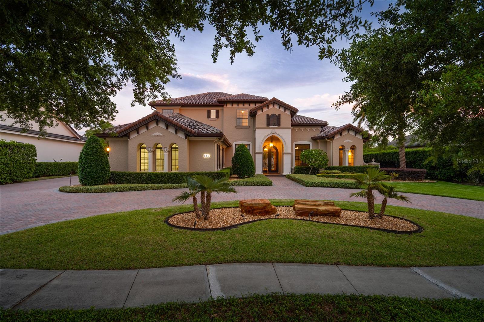Welcome to this stunning lakefront custom home located in the highly sought after guard-gated community of Lake Forest. Offering 5 bedrooms plus a private office, this exceptional residence captures breathtaking water views from nearly every room, blending luxury living with serene waterfront beauty. The home also features double-pane windows throughout, enhancing energy efficiency and comfort. Designed for both everyday living and grand entertaining, the home features a spacious first floor owner’s retreat, along with an additional guest bedroom, private office, and a custom home theater. The theater includes nine reclining tiered theater chairs, a bar, a 10-foot screen, Sony Atmos surround sound system, custom lighting, and automated blackout shades, all controlled with the touch of a button. The gourmet kitchen is designed for both everyday living and entertaining, featuring a large center island with breakfast bar and prep sink, gas cooktop, built-in ovens, reverse osmosis water filtration, and an oversized walk-in pantry. The adjoining family room showcases a custom built-in entertainment center and dramatic corner sliding glass doors that fully retract, creating seamless indoor-outdoor living. Step outside to your private resort-style lanai with a sparkling pool and spa, paver patio, built-in summer kitchen, gas fireplace, and expansive lake views, perfect for entertaining or relaxing in a peaceful waterfront setting. The second floor offers three additional bedrooms, two bathrooms, a second laundry room, and a spacious bonus room that opens to a 20x20 balcony overlooking the water. Recent updates include replacement of all HVAC systems (three replaced in 2024, one in 2023, and one in 2018). Additional upgrades include a hybrid 80 gallon hot water heater (2022), exterior paint (2019), spray foam insulation above the garage, an updated primary bathroom (2022), crown molding throughout, whole home automation, and an ADT security system. Car enthusiasts and hobbyists will appreciate the oversized four-car garage with a top-of-the-line air-conditioned workshop. Along with an insulated air conditioned attic and additional storage, this space provides approximately 1,300 square feet of additional air-conditioned space not included in the listed square footage. Community amenities include a 10,000 sq ft clubhouse, fitness center, Jr. Olympic pool, heated spa, fishing pier, tennis and pickleball courts, playground, and a 55-acre private spring-fed lake. Designated as a National Wildlife Habitat, the community also features scenic walking areas and a beautiful butterfly and pollinator garden. Conveniently located near major highways, shopping, dining, and top-rated Seminole County schools, this lakefront home offers an exceptional blend of luxury, privacy, and lifestyle.