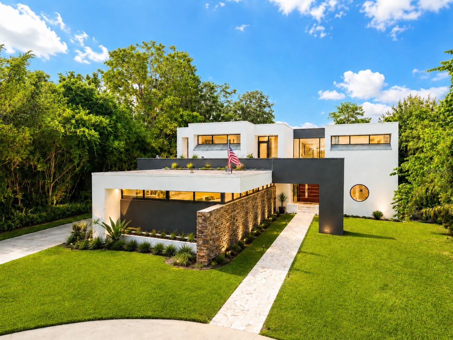 Virtually Staged. DIRECT LAKEFRONT ON BAY LAKE | MODERN ARCHITECT-DESIGNED ESTATE. More than $400,000 IN RENOVATIONS since 2024, FULL CONTROL4 SMART-HOME automation, a brand-new security system, CONCRETE-BLOCK CONSTRUCTION, and a home ENGINEERED ABOVE BASE FLOOD ELEVATION IN FLOOD ZONE X. Set on 2.395 ACRES along 110 FEET OF DIRECT FRONTAGE on Bay Lake — a private 35-ACRE LAKE in the heart of Carrollwood, rated LAKEFRONT CLASS 20, the highest direct-lakefront classification the County assigns — this one-of-a-kind CUSTOM ESTATE was designed by a celebrated Tampa architect and built by SHIMBERG HOMES. A bold, contemporary statement where every wall, ceiling line and finish was composed as a singular work of architecture, never pulled from a template. Walls of glass frame OPEN, UNOBSTRUCTED LAKE VIEWS above a resort-style backyard built for the way you actually live: a SALTWATER POOL & SPA, an oversized screened lanai, and a lake-facing outdoor kitchen, with the entire rear lawn cleared and re-sodded to the water's edge. Mornings begin with mist rising off the lake; days drift between the pool and the water; evenings close with sunset shimmering across the surface. And a GRANDFATHERED PRIVATE DOCK — yours to boat, fish, and paddle from — secures your place on the lake for generations, a right nearly impossible to obtain today. Inside, the home was made for gathering: soaring two-story glass, a sculptural FLOATING STAIRCASE, and a sunken living room anchored by a dramatic 30-FOOT WALL and a new gas fireplace. A DEDICATED HOME THEATER with full seating and a screen that drops at the touch of a button. A custom lighted bar and lounge for the nights that linger. And a CUSTOM CHEF'S KITCHEN — part of the architect's original vision — where a rare WINDOW BACKSPLASH below and a floating band of CLERESTORY GLASS above wrap the cabinetry in natural light from two heights, a true indoor-outdoor feel you rarely find anywhere, alongside brand-new appliances. Upstairs, the PRIMARY WING is a private sanctuary: a spa-inspired bath with an IMPORTED JAPANESE ZEN SOAKING TUB, a glass-walled wet room with integrated lighting, music and color, an oversized dressing room with its own built-in café bar, and a private balcony framing the lake. Estates like this — true lakefront, this pedigree, this protected — almost never trade. When they do, they do not last. Come stand at the water's edge and feel why this one is yours.