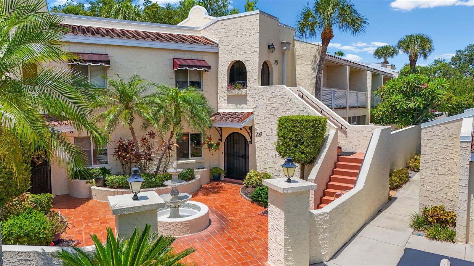 Welcome to Florida living in this beautifully maintained, first-floor, single-level residence located within the gated, Mediterranean-style community of Vizcaya. A private tiled courtyard framed by tropical landscaping and an arched wrought-iron gate welcomes you and a leaded-glass front door opens to a foyer with a tray ceiling and crown molding that carries throughout. This well-maintained 2-bedroom, 2-bath condo offers ~1,750 square feet living space with a tranquil pond view. The open living and dining concept features built-in, lit display niches and opens to the showstopper: an air-conditioned Florida room wrapped in windows overlooking the water, complete with a built-in wet bar that creates a second living room. The updated kitchen is finished with light maple cabinetry, granite counters, a glass-and-stone mosaic backsplash, and stainless appliances, including a smart LG refrigerator and Bosch double-oven range, with a breakfast bar that keeps you connected to the gathering spaces. The primary suite features dual walk-in closets and a private en-suite bath.  The guest bedroom has a full guest bath with a walk-in glass shower and granite-topped vanity. Interior laundry room, a covered carport, exterior storage, and a private fenced patio with its own separate entrance. The Vizcaya community is set on 32 lushly landscaped acres with four lakes, tropical palms, and majestic oaks offering resort-style amenities: a grand clubhouse with a social hall and dance floor, a library, a game room with billiards and table tennis, a community pool and spa, and freshly paved streets. Just minutes from IMG Academy, Sarasota-Bradenton International Airport and a short drive to Sarasota Bay, downtown Bradenton and Sarasota, and the Gulf beaches of Anna Maria Island, Longboat Key, and Lido Beach. Come experience the best of Florida living at Vizcaya.