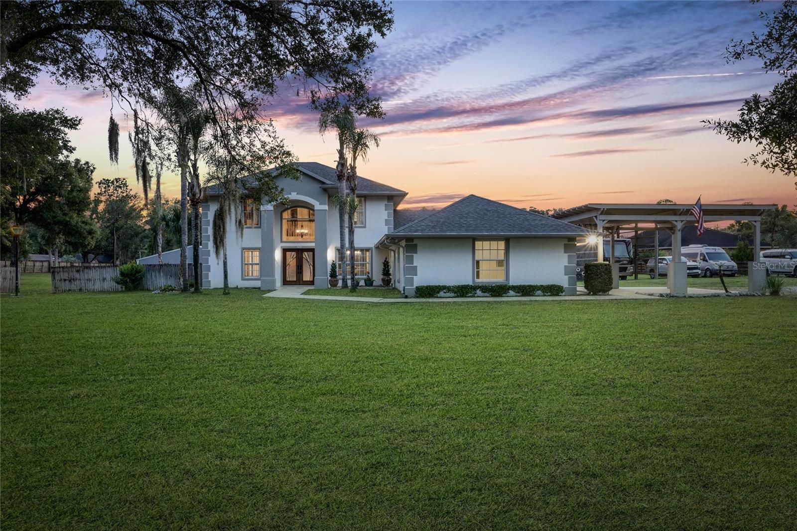 DELAND / 2.27 FULLY FENCED ACRES / LIVE + WORK + STORE + PLAY — This is the kind of property buyers wait years to find. Combining a beautifully designed pool home with extensive outbuildings, RV accommodations, and business flexibility, this 5 bedroom, 2.5 bath estate offers endless possibilities. A grand foyer welcomes you with connected formal living and dining spaces for a timeless layout and effortless entertaining. The kitchen overlooks both the family room and breakfast nook and features custom cabinetry, granite countertops, stainless steel appliances, center island, breakfast bar, and abundant prep and gathering space. The family room is highlighted by a custom wood-burning fireplace with mantle and opens seamlessly to the outdoor living area. One of the most impressive features of the home is the connection to outdoor living—the family room, formal living room, and primary suite all provide direct access to the covered patio, screened pool, and backyard retreat. The first-floor primary suite is designed as a private escape featuring his and hers walk-in closets and a spacious ensuite bath with dual vanities, glass-enclosed shower, and relaxing garden tub. Outside, enjoy the screened pool and spa, entertaining areas, and wide-open usable acreage. The original horse barn has been thoughtfully transformed into flexible-use space featuring dedicated storage along with a dog grooming area that could support a variety of uses. Beyond the attached 2-car garage, the property includes an elevated covered carport designed for oversized vehicles plus a dedicated covered RV parking area with 50-amp hookup ready for an RV, boat, or additional guests. The true showstopper is the 52x52 insulated metal outbuilding with bathroom, 4K camera security system, 50-amp service, and its own separate gated entrance allowing independent access from the residence—currently operating as a dog training facility but offering extraordinary flexibility for a business operation, workshop, contractor space, indoor recreation, vehicle collection, storage facility, kennel operation, guest accommodations, and more (buyer to verify intended use). Just minutes from DeLand while offering privacy, functionality, and unmatched versatility—this is more than a home, it’s an opportunity.