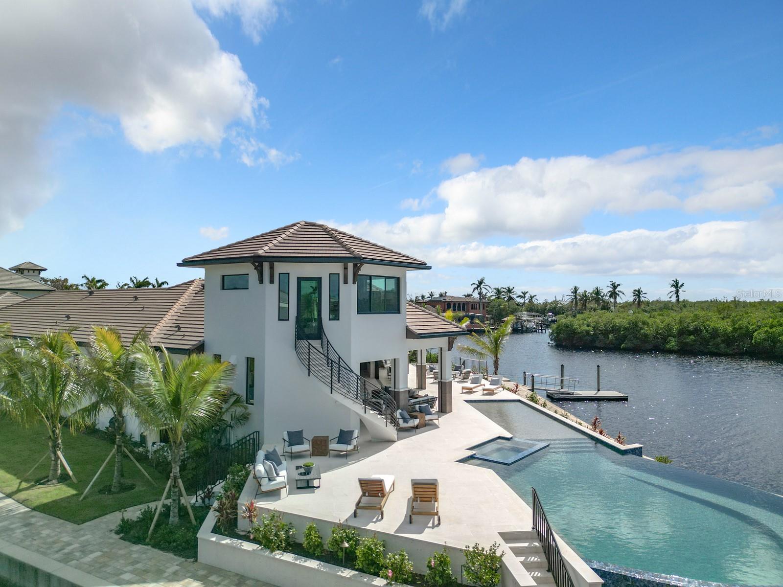 Don't miss this boater's paradise with direct (no bridges) deep water Gulf Access only minutes from the river. 
This one of a kind property features ultimate privacy in this exclusive, gated waterfront community.  Brand new premium construction by award winning builder, Windward Construction, on a near triple corner lot with nearly 500 feet of seawall, all of which has extra elevation to keep you high and dry.  This exquisite smart home features nearly 7000 square feet under air including a massive garage with rear bay doors for ease of transferring supplies to your boat.  A boater's paradise with deep water direct access to the Gulf of Mexico.  Station your yacht on the 100 foot floating dock with ramp and store your tender boat on its own lift.  Utilize the  additional 7,500 lb covered lift for your every day watercraft.  A total of 5 bedrooms with designated full bathrooms and 2 half bathrooms, one of which is accessible from the pool area.  The in law suite with private entrance is an impressive 2 bed, 2 bath alluring space with its own private patio.  A welcoming open floor plan features a great room with a backlit granite wall with built in linear electric fireplace and sublime wood beams on the cathedral ceilings.  The remarkable outdoor area includes a summer kitchen with built in gas grill, expansive seating area including gas fireplace area, a heated infinity edge pool with integrated spa and lengthy shallow walkout.  The spiral outdoor stairwell takes you to a bonus air conditioned room with a breathtaking view which can be utilized in so many different ways.  The elegant shell stone tile flows through the home and beyond the pocket sliders bringing a seamless transition to the expansive outdoor living area. This is a custom built home with the Florida lifestyle very much at the forefront of every aspect of construction and  design including a 1000 gallon propane tank that will operate the Generac home generator for weeks!  Impact doors and windows and dual electric hurricane and insect screens provide added protection to the lanai area.  Located just off McGregor Blvd., minutes from beaches, restaurants, and shopping and only 6 miles from the private airport, Page Field and 16 miles from Fort Myers International. The staging furniture has been removed and the home is ready for quick occupancy.