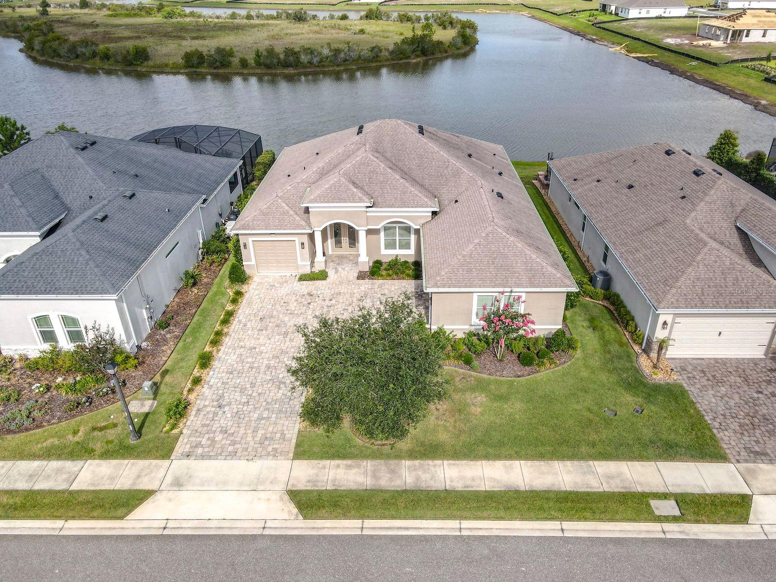 One or more photo(s) has been virtually staged. Elevated waterfront living in this exceptionally upgraded luxury residence located in the award-winning Lakes of Mount Dora, one of Central Florida’s premier 55+ gated communities. Perfectly positioned on a premium water lot, this home blends refined craftsmanship, modern efficiency, and timeless design—creating a lifestyle defined by comfort, sophistication, and serene lake views.

Step inside to Land Blanc 21" porcelain tile throughout, anchored by a custom foyer floor inlay and ceiling accent that set an immediate tone of elegance. High ceilings, crown molding, and tray details enhance the open-concept layout, while expansive windows frame tranquil water vistas.

The gourmet kitchen is a true showpiece, featuring Maple Chiffon soft-close cabinetry, quartz countertops, a matching quartz backsplash, and a natural gas cooktop. Two tankless gas water heaters ensure endless hot water and energy efficiency. The breakfast nook is elevated with a drop-tray ceiling, adding architectural depth to the space.

A dedicated media room/office offers flexibility and includes a private exit to the enclosed sunroom, fully finished with its own HVAC system for year-round enjoyment. The central vacuum system adds convenience throughout the home.

The luxurious primary suite provides a peaceful retreat with water views, spa-inspired finishes, and generous walk-in closets. Additional guest rooms provide comfort and privacy for visitors or multi-use needs.

Car enthusiasts and hobbyists will appreciate the two separate garages with space for three cars, complete with epoxy-sealed flooring and built-in storage shelving—a thoughtful blend of function and refinement.

Outside, the covered lanai has room for a pool and invites you to unwind with panoramic water views, gentle breezes, and unforgettable sunsets. 

Residents of Lakes of Mount Dora enjoy world-class amenities, including a resort pool, clubhouse, fitness center, pickleball, walking trails, and a vibrant social calendar—all just minutes from historic downtown Mount Dora’s dining, boutiques, and waterfront festivals.