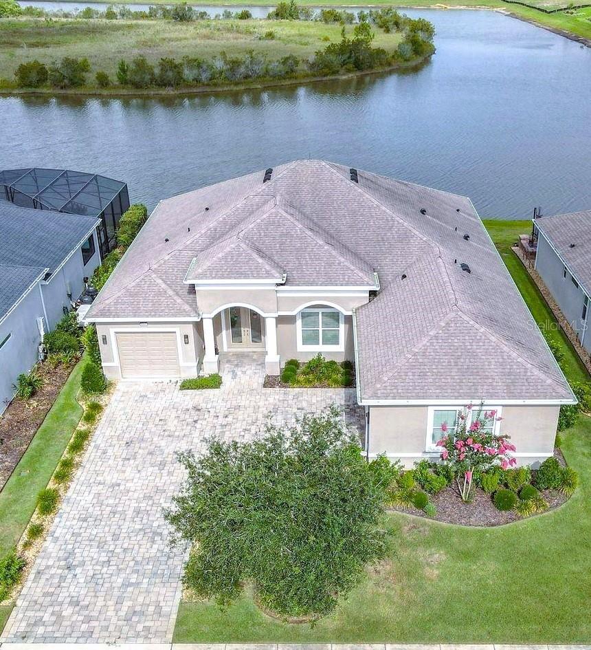 One or more photo(s) has been virtually staged. Set on a peaceful waterfront lot with wide-open lake views, this custom-built 2019 Medallion Home Santa Maria model offers 3 bedrooms, 2 baths, and the kind of refined Florida living buyers dream about.

The home includes Land Blanc 21" porcelain tile throughout, cathedral ceilings, large crown molding, tray accents, interior 8-ft doors, a central vacuum system, two tankless gas water heaters, Double pane, Low-E windows and sliders, garage storage shelving, foyer ceiling detail, gas cook top, gutters, paver walkways, lanai and driveway. Lightning rods added for enhanced storm protection. 

The gourmet kitchen features Maple Chiffon soft-close, full extension upgraded cabinetry, quartz kitchen countertops with waterfall edge and a full quartz backsplash. A drop-tray ceiling defines the breakfast nook, and the large aquarium glass window creates a dramatic focal point that enhances the entire living space. The enclosed sunroom, complete with its own dedicated HVAC system, offers year-round comfort and seamless indoor-outdoor living, with huge lake views.

The main living areas have an open layout with large windows that bring in natural light and water views. A separate media room with lake views provides flexible living space and direct access to the enclosed sunroom, which is fully finished with its own HVAC system for year-round use.

The primary suite includes water views and a well-appointed ensuite with a walk-in shower, custom cabinetry, and generous walk-in closets. Guest rooms are well-sized and provide privacy for visitors or workspace needs.

Two separate garages provide three-car capacity, epoxy flooring, and built-in storage, ideal for car enthusiasts or hobbyists.

The covered lanai overlooks the water and has ample room for a future pool, creating a versatile outdoor living area with sunset views.

Residents enjoy resort-style amenities, including a beautiful pool with a beach entry, clubhouse with full social Calander, fitness center, pickleball, walking trails and RV- Boat storage— just minutes from historic downtown Mount Dora’s dining, shops, and waterfront events.