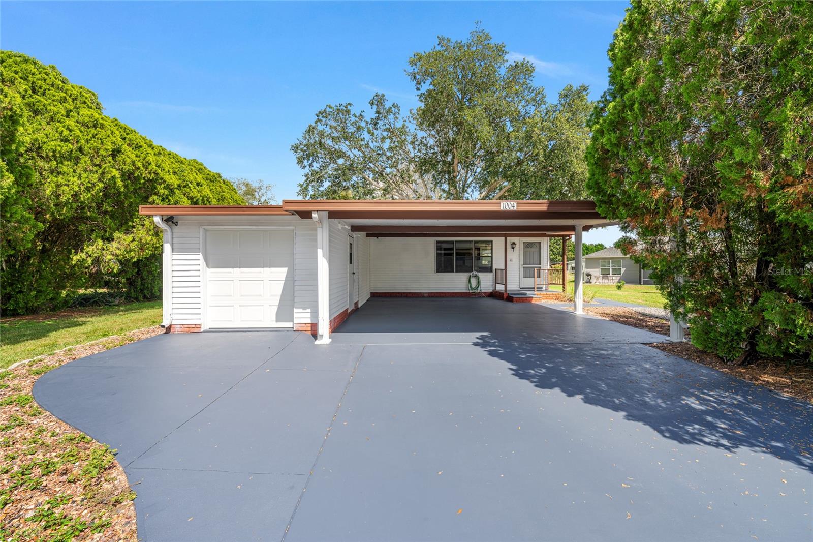 Fresh updates, flexible living space, and a Lady Lake location close to The Villages, Spanish Springs, golf, shopping, restaurants, medical offices, parks, and lakes. Inside, the home feels open and easy to live in with new flooring, fresh paint, vaulted ceilings, large windows, and built ins that add storage and character. The kitchen offers warm wood cabinetry, generous counter space, a center cooktop island, and a wall oven, all connecting easily to the main living areas. A screened lanai adds usable Florida living space, while the oversized covered carport, long driveway, and attached storage area give you room for vehicles, golf cart parking, tools, hobbies, or seasonal items. Mature landscaping gives the property a more private feel, and the location keeps everyday conveniences close without feeling boxed in. Clean, refreshed, and easy to enjoy near The Villages.