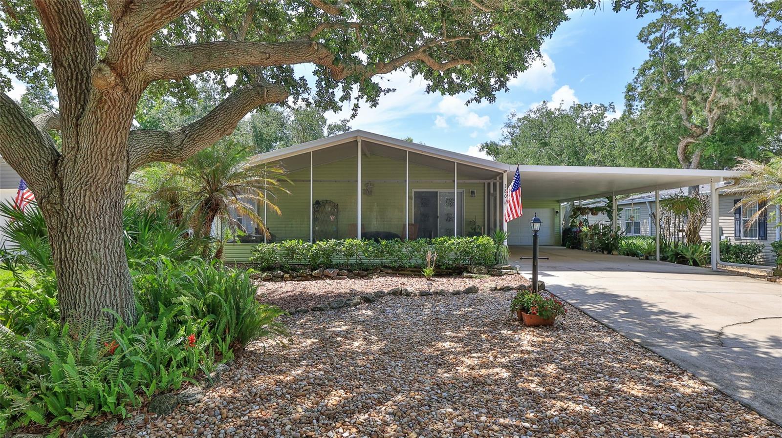 Gorgeous two bedroom, two bath home is perfectly situated on a beautifully landscaped lot directly across from one of the community’s scenic greenbelt areas. Start your day with a cup of coffee on the front screened patio while enjoying peaceful views and abundant wildlife. Parking is plentiful with an attached garage and double-car carport. This split floor plan home features an updated kitchen with hickory cabinetry and quartz countertops, vaulted ceilings, laminate and tile flooring throughout, extra closet shelving and more. Roof installed August 2021. This inviting home combines comfort, convenience and natural beauty in an exceptional setting. Not a lot rental community, own your own land. Lighthouse Cove is a riverside gated community where golf carts are a second means of transportation. Enjoy a large, heated swimming pool, recently renovated clubhouse, pickleball courts, shuffleboard, boat launch for shallow water boats, recreational picnic area on the river, a fishing pier and weekly events at the clubhouse. It is a boating/fishing/shrimping paradise located a short distance from the Mosquito Lagoon. Watch the rockets launch from the fishing pier. Don’t miss out on a great opportunity to live in Paradise. A must see! All measurements approximate!