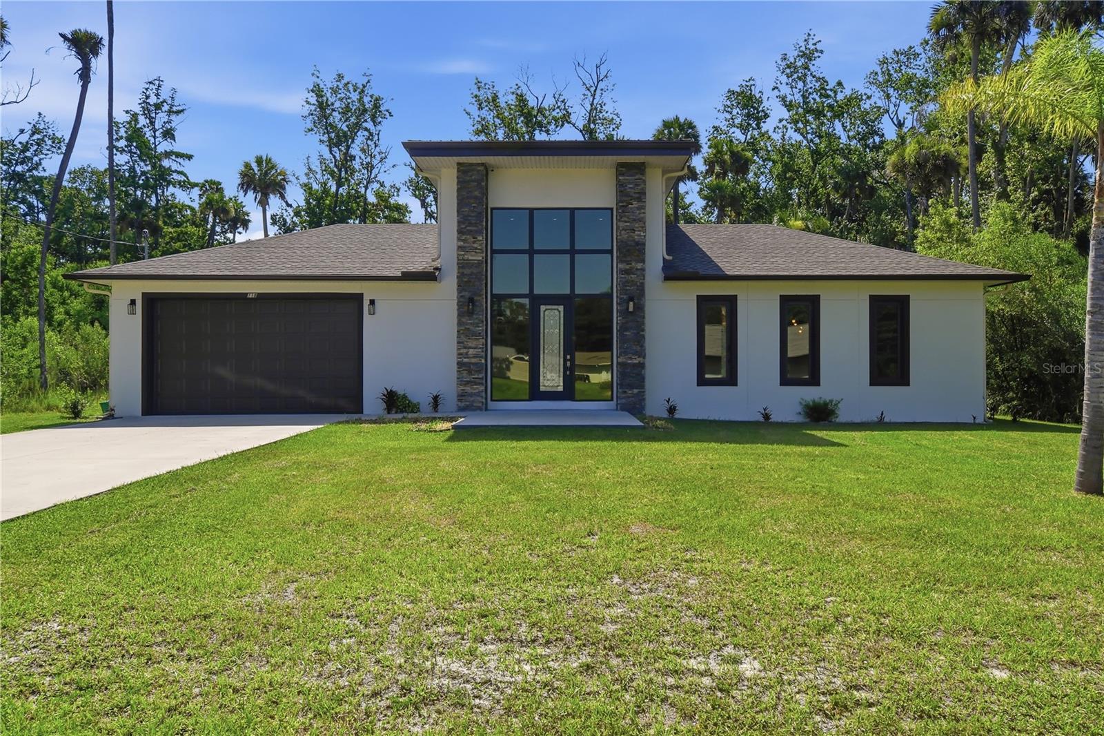 Experience contemporary luxury and exceptional craftsmanship at 118 Blare Drive, a custom-built 2024 residence nestled on a private preserve lot in the highly sought-after Woodlands neighborhood of Palm Coast. Offering over 3,200 square feet of thoughtfully designed living space, this stunning home features 4 bedrooms, 3 bathrooms, and an open-concept floor plan that perfectly blends elegance with everyday comfort.
From the moment you arrive, the home's striking modern architecture, stacked-stone accents, and dramatic floor-to-ceiling glass entry create an unforgettable first impression. Inside, approximately 18-foot ceilings and expansive windows fill the home with natural light, enhancing the spaciousness of the great room.
At the heart of the home is a spectacular floor-to-ceiling double-sided stone fireplace that serves as both a stunning focal point and a seamless connection between the indoor living space and the outdoor entertaining area. Whether relaxing inside or enjoying an evening by the pool, this unique feature creates an inviting atmosphere year-round.
The chef-inspired kitchen is designed for both functionality and style, featuring granite countertops, an oversized center island, soft-close cabinets and drawers, abundant storage, a designer tile backsplash, and generous prep space, ideal for entertaining or everyday living.
The spacious owner's suite offers a peaceful retreat with his-and-hers walk-in closets and a beautifully appointed ensuite bath. A thoughtfully designed split-bedroom layout provides privacy and comfort for family members and guests.
Step outside to your private backyard oasis where a sparkling saltwater pool with a relaxing Baja shelf invites you to unwind while enjoying peaceful preserve views with no rear neighbors. The covered lanai and outdoor side of the double-sided fireplace create an incredible setting for entertaining, relaxing, or enjoying Florida's outdoor lifestyle in every season.
Additional features include tile plank flooring throughout the home, designer lighting, an indoor laundry room, oversized windows, and a spacious two-car garage.
From peaceful mornings overlooking the preserve to evenings spent around the double-sided fireplace and weekends relaxing in the saltwater pool, 118 Blare Drive offers the perfect blend of luxury, comfort, and Florida living. This is more than a home, it's a place where lasting memories are made.