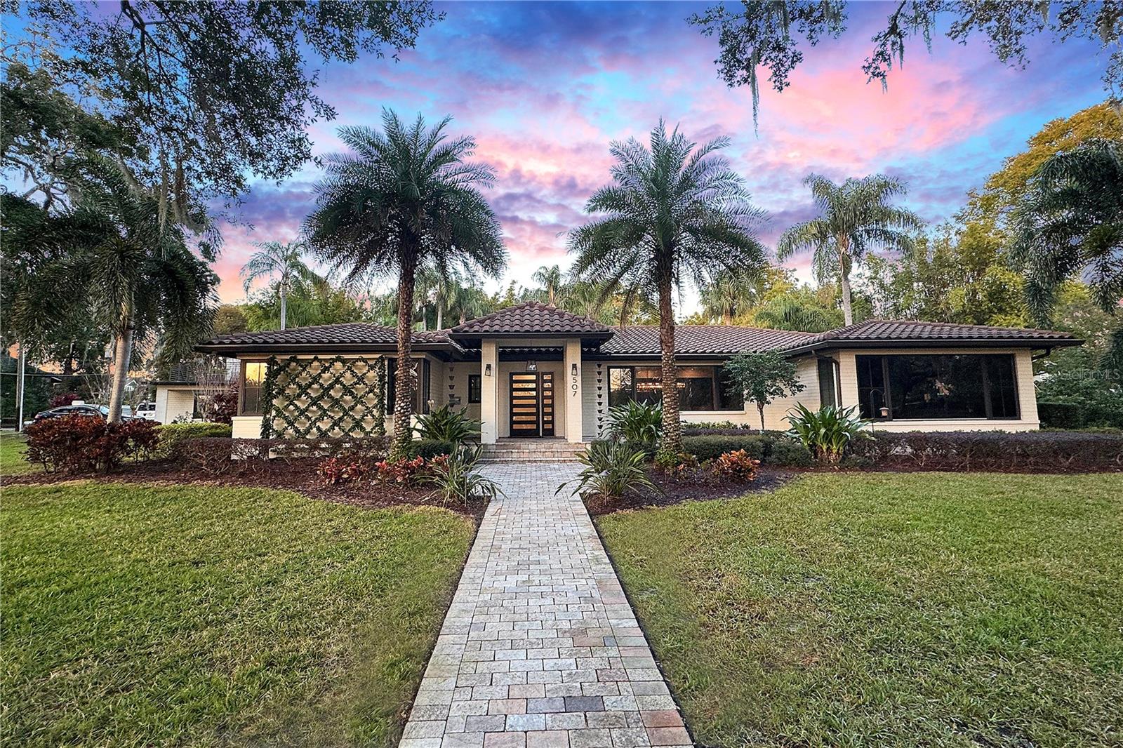 Step into your private urban oasis in the historic Lake Cherokee neighborhood, right in the heart of downtown Orlando. Nestled on a full-acre corner lot, this stunning mid-century modern ranch-style home offers the perfect blend of luxury, comfort, and convenience. Just a short walk to the Dr. Phillips Center, Lake Eola, Thornton Park, restaurants, and downtown’s vibrant business district, this one-of-a-kind property offers resort-style living at its finest.

This 5-bedroom, 4.5-bath home is surrounded by mature landscaping, including majestic oak trees, making it one of Lake Cherokee’s most beautiful properties. The completely renovated chef’s kitchen features waterfall quartz countertops, an oversized Subzero refrigerator and freezer, a Dacor appliance suite with a 48-inch range, hood, and microwave, plus a Dacor four-bottle wine dispenser, two Subzero refrigerator drawers, and a dual-zone wine fridge—everything you need to entertain in style.

For wine enthusiasts, the newly installed 1,300-bottle, temperature-controlled wine cellar with vintage view racks, custom flooring, and lighting sets the stage for unforgettable dinners. A dry bar with a cork countertop and integrated lighting enhances the dining experience. Integrated Sonos speakers throughout the home, including the outdoor living spaces, ensure seamless entertainment inside and out. The home features refinished original hardwood floors, complemented by a beautifully renovated living room with an expansive fireplace, quartz countertops, and built-in media storage.

Start each day with serene views of swans gliding across Lake Cherokee from the luxurious primary suite. The suite includes an attached office with a built-in desk, breakfast bar, and expansive his-and-hers walk-in closets. The spa-inspired primary bath boasts a soaking tub, double shower, double vanity, and a Toto smart bidet toilet. The guest bedrooms are generously sized, each with oversized closets, while the remodeled guest bath features marble, granite, and a rain shower.

The backyard feels like a secluded retreat, surrounded by mature bamboo. An outdoor kitchen, complete with a grill, ceramic searing burner, double burners, steamer, deep fryer, and wok stations, overlooks the expansive saltwater pool and spa with an outdoor shower and pool bath. The recently updated mother-in-law suite includes new floors, air conditioning, energy-efficient doors, and a gas water heater. A walkout balcony with an extended rooftop deck offers a spectacular view of Lake Cherokee.

This home has undergone significant infrastructure upgrades, including complete re-piping, new insulation, outdoor lighting, and a security gate for added privacy and peace of mind.

Don’t miss the chance to call this extraordinary property home—where modern luxury meets historic charm, all within walking distance of downtown Orlando’s best offerings. Schedule your private showing today!
