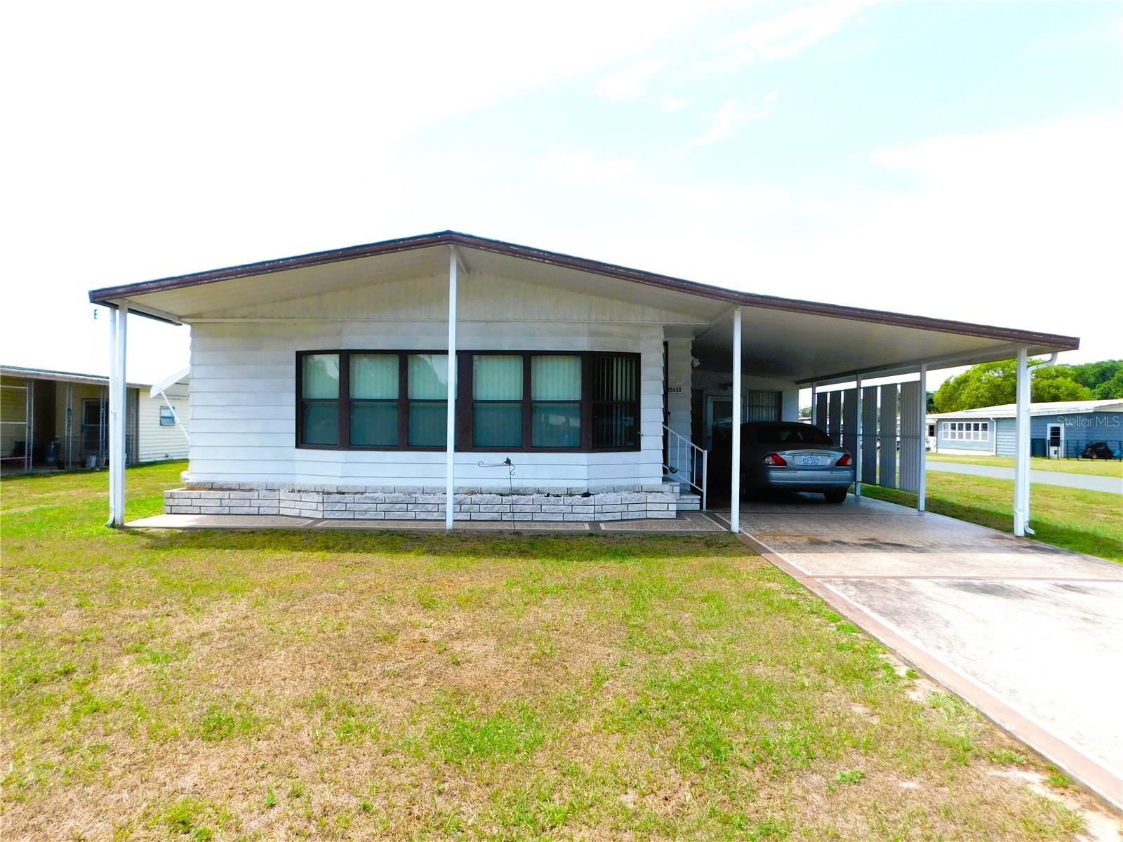 Want to escape the cold, snowy north and spend a few months in the beautiful Florida sunshine? Want to OWN your land with NO expensive lot rent? Come check out Gem Estates 55+ community where you OWN your land with a low annual HOA fee of $300 which includes water and recreational facilities. Bring Fido because the community allows pets and one of the few 55+ communities that allows large dogs. This lovingly maintained 2BR/2BA home is located on a big corner lot. The home has a nice open concept between the kitchen, dining and living rooms. There's a large family room area which looks out to the front of the home and is a great additional space for entertaining family and friends. Both bedrooms are good size and have carpet, ceiling fans and walk-in closets. The master has ensuite bathroom with dual sinks and step-in shower. The guest bath is conveniently located opposite bedroom two and can also be accessed from the inside laundry. The laundry room has a built-in desk area and offers access to the 12x21 Florida room which can be cooled by a window AC unit.  Bring your tools and gadgets because just off the Florida room is a workshop with work bench and lots of space for storage. There's a small detached 6x8 metal building in the backyard for additional storage space.  The community is located close to shopping, restaurants and top-notch medical facilities. Schedule your appointment today. Don't let this one get away!