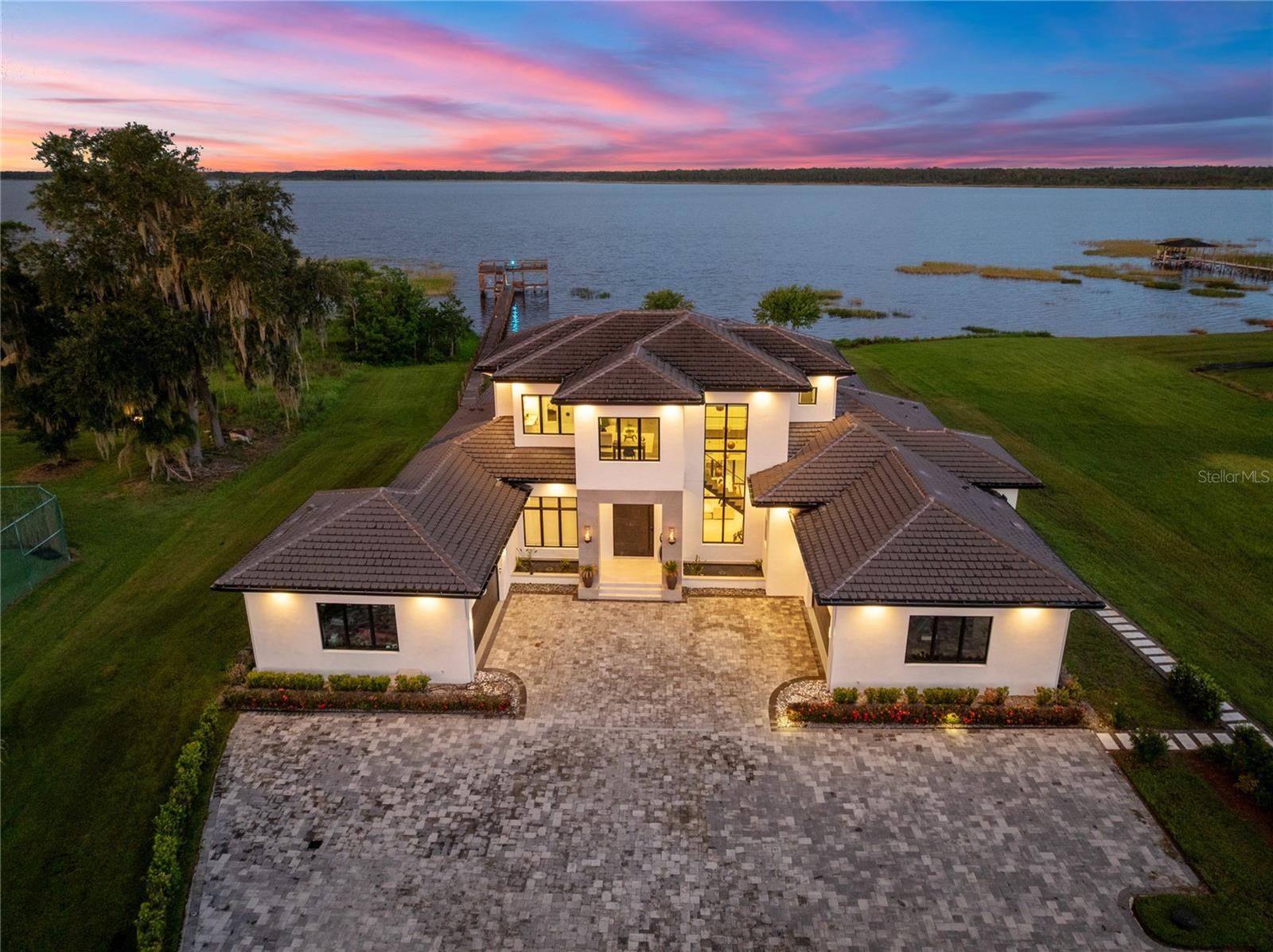 Virtually Staged. Behind a private gated entrance, this Parade of Homes award-winning custom estate represents one of the last opportunities to own a true legacy waterfront property in Lake Nona. Set on 2.07 acres with approximately 140 feet of pristine Lake Hart frontage, this architectural masterpiece features one of the lake’s largest double-decker docks, creating an unmatched setting for boating, fishing, entertaining, and unforgettable sunsets. Built by Valdara Homes in 2022 and Certified by Building Biology Environmental Consultants, the home combines contemporary architecture, wellness-focused design, exceptional privacy, and resort-inspired living.

Offering 7,058 square feet, the residence includes six bedrooms, five full baths, one half bath, and a four-car garage. A custom pivot door opens to soaring 20-foot ceilings, warm wood accents, architectural concrete details, and walls of glass overlooking the lake. The open-concept living areas flow effortlessly into the chef’s kitchen, featuring Sub-Zero refrigeration, a Wolf gas range with griddle, custom cabinetry, concrete countertops, an oversized island, concealed walk-in pantry, integrated Sonos audio, and pocketing sliding glass doors that blend indoor and outdoor living.

The first-floor primary suite offers a private lakeside retreat with motorized blackout shades, custom wardrobes, built-in storage, and a two-sided fireplace shared with the spa-inspired bath. A second first-floor bedroom with a private entrance and full bath is ideal for guests or multigenerational living. Upstairs features additional bedrooms, a loft with lake views, a dedicated office, and a flexible bonus room.

Outdoor living is designed for year-round enjoyment with a covered lanai, summer kitchen, heated saltwater pool, gas spa, outdoor shower, and beautifully landscaped grounds. Extending into Lake Hart is the spectacular double-decker dock with covered boat lifts, expansive entertaining areas, and an elevated observation deck.

The detached guest residence offers more than 2,000 additional square feet with one bedroom, one bath, a kitchenette, private entrance, and a massive flex space ideal for an executive office, gym, indoor sport court, in-law suite, studio, or home business.

Additional features include a full-size tennis court, workshop, FGBC Platinum certification, low-VOC construction, whole-home water and air filtration, Ethernet wiring, well irrigation, and the ability to support off-grid living with a private well and Starlink compatibility if desired.

Just minutes from Lake Nona Medical City, AdventHealth, Nemours Children’s Hospital, the VA Medical Center, USTA National Campus, Lake Nona Town Center, Orlando International Airport, and major highways, this is one of Lake Nona’s true trophy estates. With over two acres, 140 feet of private waterfront, an award-winning design, one of the lake’s largest docks, and an irreplaceable location, this is a once-in-a-generation opportunity. Schedule your private tour today.