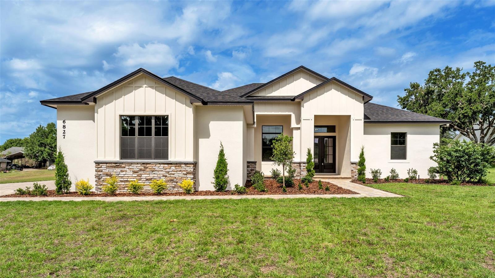 One or more photo(s) has been virtually staged. Introducing a masterfully crafted, brand-new custom residence by LK&T Construction, completed in 2026 and set on a pristine one-acre homesite with no HOA—a rare combination of luxury, privacy, and freedom. From the moment you enter, the home reveals its exceptional quality through continuous wood-look tile flooring, soaring ceilings, and meticulously selected finishes that create a seamless, sophisticated aesthetic throughout. The grand living room serves as the centerpiece of the home, anchored by a striking stone electric fireplace and elevated by an architectural beam ceiling that adds depth and character. Expansive sightlines draw you into the designer kitchen—an impressive culinary space appointed with stainless steel appliances, granite countertops, a stylish backsplash, a dedicated coffee bar, and a custom built-in pantry. The oversized island offers both function and elegance, making it the perfect gathering point for entertaining. The primary suite is a true retreat, featuring trey ceilings and a spa-inspired ensuite bathroom with dual vanities, a walk-in tiled shower, a stand-alone soaking tub, and a custom-designed walk-in closet. The split layout enhances privacy, with two additional bedrooms sharing a beautifully finished guest bath. The fourth bedroom stands out with its generous size and private bathroom, offering the flexibility of a secondary primary suite—ideal for guests or multigenerational living. A dedicated office near the entry provides a refined and quiet workspace. Outdoor living begins with a pavered patio overlooking the expansive yard, offering endless possibilities for a future pool, workshop, or personalized outdoor oasis. With close proximity to retailers and the Polk Parkway, this residence delivers an unparalleled blend of luxury craftsmanship, modern comfort, and everyday convenience—all without the restrictions of an HOA.