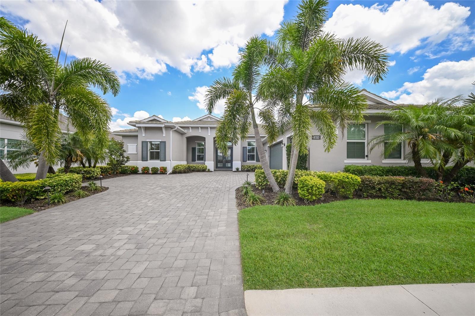 Nestled behind the gates of The Isles at Lakewood Ranch, this exceptional highly upgraded Captiva Collection residence blends refined luxury with effortless Florida living on an oversized 80’ x 150’ homesite. Built in 2020, the thoughtfully designed home offers 3 bedrooms, 3 full baths, a powder room, office/flex space, and nearly 2,900 square feet of beautifully curated interiors in the heart of Lakewood Ranch.
From the moment you enter, elevated finishes and custom details set the tone — including hardwood floors in the office and primary suite, coffered ceilings with decorative beams, crown molding, plantation shutters, upgraded lighting fixtures, and a built-in credenza in the great room. Pocket sliding glass doors create a seamless connection to the expansive lanai, where resort-style outdoor living takes center stage.
The custom pool features travertine marble decking, a sun shelf, and a Paramount self-cleaning system, all framed by lush professional landscaping and outdoor lighting. The outdoor kitchen is equally impressive with granite counters, backsplash, and dedicated cabinetry for effortless entertaining under the Florida sky.
The gourmet kitchen offers upgraded cabinetry and counters, double pantry storage, wine refrigerator, and generous gathering space overlooking the great room and pool. The luxurious primary suite includes a standalone soaking tub, custom cabinetry, and spa-inspired finishes.
Additional highlights include hurricane impact glass throughout, whole-house gutters with underground pop-ups, radiant barrier insulation, Kohler whole-house generator with transferable 10-year warranty, Mitsubishi mini-split system in the garage, water softener and charcoal filtration system, surround sound and home WiFi enhancements, storage cabinetry and workbench in the garage, and new LG washer and dryer (2026).
Perfectly positioned near world-class golf, dining, shopping, and the vibrant lifestyle amenities that define Lakewood Ranch, this home is polished, private, and designed for living beautifully.