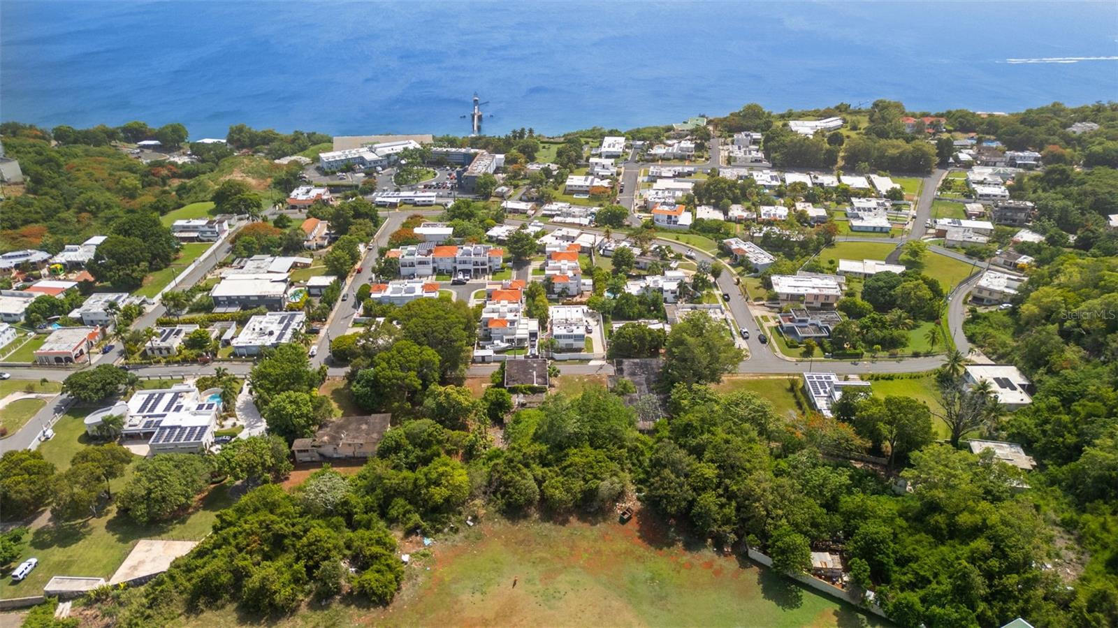 Exceptional 4-Acre Flat Multi-Residence Estate in the Exclusive Villa Lydia Community in Aguadilla, Puerto Rico. Welcome to an extraordinary opportunity to own approximately 4 flat acres in the exclusive Villa Lydia neighborhood of Aguadilla. Offering ocean views, multiple residential buildings, and existing structures that can be converted into additional units, this one-of-a-kind estate presents exceptional income-producing potential. The property's expansive, flat terrain provides ample space for amenities such as a swimming pool, tennis or pickleball courts, basketball courts, or other recreational facilities, making it ideal for creating a luxury retreat or resort-style environment. With its generous layout and development potential, the property can be transformed into a wide range of income-producing ventures, including a boutique hotel, vacation rental complex, wellness retreat, event venue, corporate retreat, or multi-family investment. Whether envisioned as a private family compound or a premier hospitality destination, this remarkable property offers endless possibilities in one of Aguadilla's most desirable neighborhoods.
The centerpiece of the estate is a spacious two-story main residence featuring 4 bedrooms and 2 bathrooms, a welcoming living room, kitchen, expansive terrace, and a balcony with beautiful ocean views. The first floor also includes a versatile studio, ideal for a home office, guest suite, creative space, or recreational area.

The property also includes a two-story apartment building with two generously sized residences. The upper-level apartment features 3 bedrooms, 2 bathrooms, a private balcony, kitchen, living room, laundry area and its own garage, while the first-floor apartment also offers 3 bedrooms, 2 bathrooms, and a dedicated garage, kitchen, living room, laundry area, providing comfortable accommodations for long-term tenants or vacation guests. Located behind this building is an additional 2-bedroom, 2-bathroom apartment complete with a living room, kitchen, laundry area, and private garage, offering even more flexibility for rental income or extended family living. Further enhancing the property's value is a second apartment building comprised of four spacious units, each offering 3 bedrooms, 2 bathrooms, a kitchen, living room, laundry area, private balconies, garages, and impressive high ceilings. The building also includes ample storage space, adding convenience for owners and tenants alike. The estate also features a flat 981-square-meter vacant lot with ocean views, providing endless possibilities for future development, recreational amenities, landscaped gardens, or additional construction. Ideally located just a minute away from downtown Aguadilla, residents enjoy easy access to restaurants, shopping, schools, and essential services. Some of Puerto Rico's most celebrated beaches, including Crash Boat Beach, are only a short drive away, while Rafael Hernández International Airport (BQN) and Ramey Air Force Base area are 10 minutes away. Whether you're seeking a remarkable private estate, a thriving income-producing investment, or a unique development opportunity in Aguadilla's most desirable community, this exceptional property offers unmatched versatility, location, and long-term value.