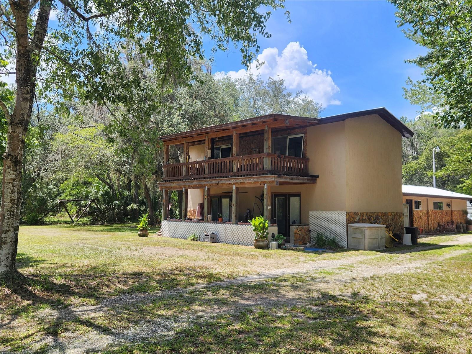 Escape to the peace and privacy of country living on 5 acres featuring a partially cleared, fenced pasture and wooded acreage for added privacy. The two-story home offers 3 bedrooms, 3 full bathrooms and a versatile bonus room that's perfect for a home office, den or potential 4th bedroom. The spacious, updated eat-in kitchen is ideal for both everyday living and entertaining with its hickory cabinets, granite countertops, a new dishwasher and 2 pantries. The living room has a brick fireplace and French doors that open to the covered front porch. The first floor primary suite provides a peaceful retreat with rustic wood accents and French doors leading to the 12x30 screened porch featuring an outdoor cooking area. The primary bathroom includes a walk-in closet, double sink vanity and a tiled walk-in shower with dual shower heads. A beautiful wood staircase leads to the 2nd floor where you'll find 2 guest bedrooms and a full bathroom. Both bedrooms feature hardwood floors and sliding glass doors that open onto a covered balcony overlooking the property. The property has paved road frontage and offers easy access to the Orange Springs boat ramp located at the end of the road for your fishing and boating enjoyment on the Ocklawaha River. Conveniently located between Ocala, Gainesville and Palatka.