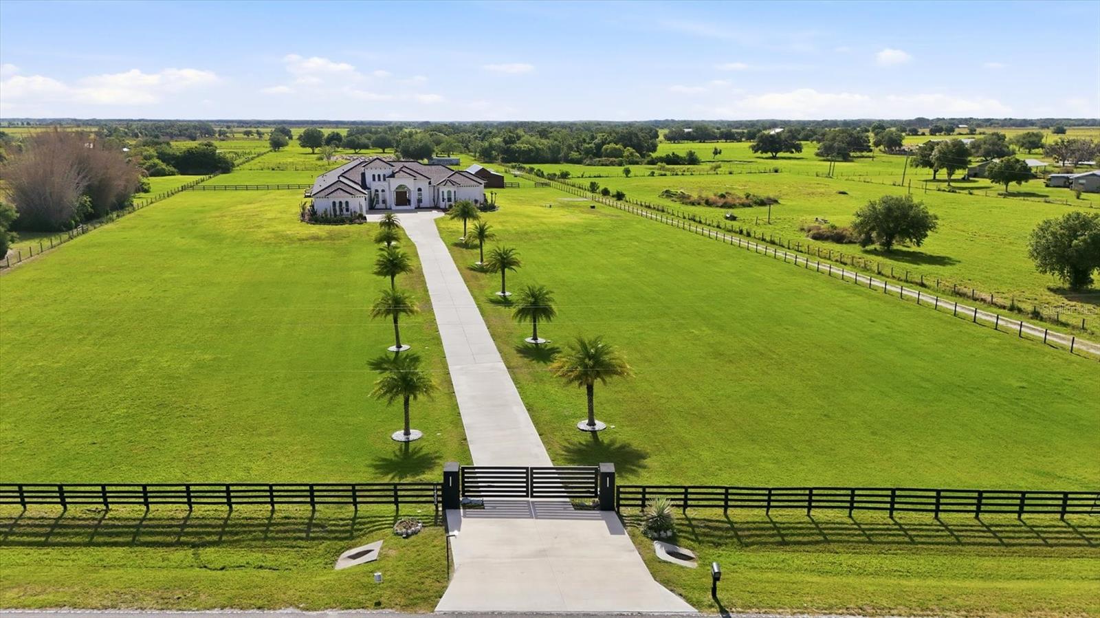 One or more photo(s) has been virtually staged. Welcome to one of the most extraordinary private estates in the area.  Positioned on six fully fenced acres of pristine land. From the moment you enter through the automatic gate and travel the long palm-lined driveway, you know you’ve arrived somewhere special. This spectacular residence features soaring ceilings and expansive open living spaces that create an immediate sense of grandeur. Every detail has been thoughtfully designed. From the extravagant landscaping with custom lighting and full irrigation system to decorative rock accents that enhance drainage while elevating the property’s curb appeal. Inside, you’ll find one of the most impressive floor plans available. Multiple wet bar stations, private corridors with direct pool access and breathtaking country views elevate everyday living. The primary suite is a private retreat of its own, featuring oversized boutique-style closets and a built-in concrete safe room. The chef’s kitchen serves as heart of the home, ideal for entertaining on a grand scale or enjoying quiet evenings in. In addition to the spacious bedrooms, two large flex rooms offer endless possibilities like an executive office, a golf simulator lounge, private theater room, fitness studio or creative space. Go outside to a resort-inspired pool with a fresh modern design, outdoor kitchen, covered lounging areas, surround sound throughout and ambient evening lighting that creates an unforgettable atmosphere. Whether hosting game nights, relaxing with friends or enjoying peaceful sunsets, this outdoor space delivers. The fully equipped barn makes this an equestrian property. The land allows animals to roam freely and comfortably, a rare lifestyle opportunity. Surrounded by growth and future development, including Terranova Equestrian Center just across the way and golf courses minutes away, this estate stands unmatched in quality, scale and location. This is more than a home, it’s a private compound with long-term upside and limitless potential.