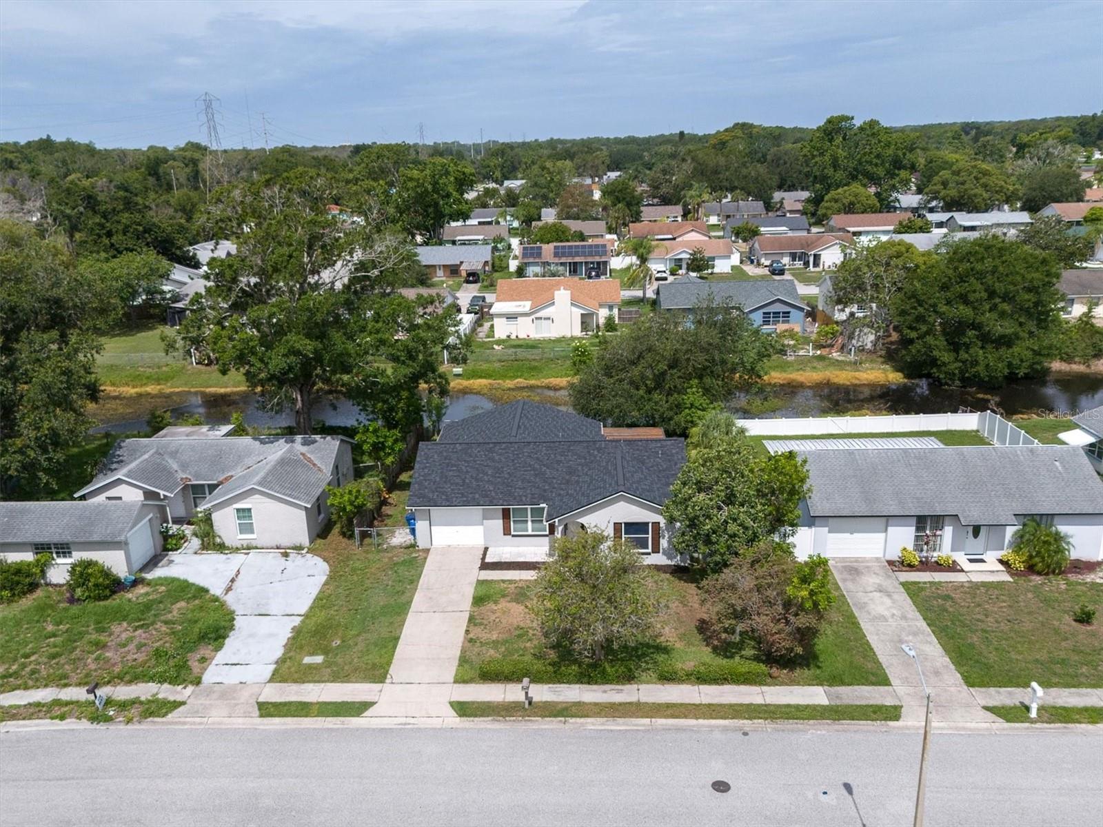 PRIDE OF OWNERSHIP SHINES ~ COMPLETELY REMODELED HOME IN A PRIME TRINITY LOCATION! This beautifully updated 2-bedroom, 2-bathroom home with a 1-car garage offers 1,449 square feet of comfortable living space and over $60,000 in recent improvements. Situated on a picturesque canal, this move-in-ready property combines modern updates with major system upgrades that today's buyers will appreciate. Step inside to discover luxury vinyl plank flooring throughout and a completely remodeled kitchen featuring stylish cabinetry, stunning quartz countertops, and a full suite of LG appliances (2019), including a smart washer and dryer. Both bathrooms have been tastefully renovated, creating a fresh and modern feel throughout the home. Major investments provide exceptional value and peace of mind, including a NEW ROOF (2025) with a transferable 50-year warranty, NEW HOT WATER HEATER (2025), NEW AC SYSTEM (2022), and PGT hurricane-rated impact windows and sliding glass door installed in 2010. The open and inviting floor plan flows seamlessly to the outdoor living areas where you can relax and enjoy tranquil canal views with a fully fenced yard. A stylish Pergola draped in String lights is a charming spot to enjoy morning coffee or weekend BBQ. Whether you're looking for a year-round residence, seasonal retreat, or investment opportunity, this home checks all the boxes with updated interiors, quality improvements, and a desirable waterfront setting. NO HOA! FLOOD ZONE A REQUIRES FLOOD INSURANCE. Conveniently located near top rated schools, shopping, dining, medical facilities, beaches, and recreation, this exceptional property offers the perfect blend of comfort, convenience, and Florida lifestyle living. Make your move today!