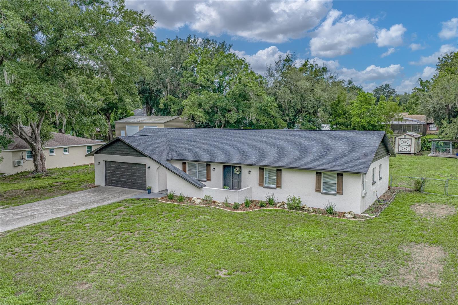 Welcome home to the perfect blend of modern updates, comfortable living, and peaceful country charm. Nestled on nearly half an acre in beautiful Dade City, this beautifully renovated three-bedroom, two-bathroom home offers the space you’ve been searching for, along with the stylish finishes today’s buyers love.  From the moment you arrive, you’ll appreciate the welcoming front porch courtyard—a quiet place to enjoy your morning coffee before stepping inside. A charming foyer greets you and sets the tone for the thoughtfully updated interior. Just off the entry, the formal dining room provides incredible flexibility and is currently arranged as a home office and guest space, making it easy to adapt to your lifestyle.  At the heart of the home, the recently remodeled kitchen is sure to impress. Featuring beautiful new cabinetry, gleaming stone countertops, stainless steel appliances, a spacious closet pantry, and a convenient breakfast bar, this space was designed with both everyday living and entertaining in mind. The open layout flows seamlessly into the dining area, creating the perfect gathering place for family meals and holiday celebrations alike. French doors extend the living space outdoors, leading to the covered lanai where indoor and outdoor entertaining come together effortlessly.  The inviting living room offers a warm and comfortable atmosphere, complete with sliding glass doors that open to the covered and screened porch, allowing you to enjoy Florida’s beautiful weather year-round while overlooking the expansive backyard.  Luxury vinyl plank flooring flows throughout the home, complemented by fresh neutral paint that creates a bright, timeless backdrop ready for your personal style. Both bathrooms have been tastefully renovated with modern finishes, providing a fresh, spa-inspired feel. The spacious primary suite serves as a relaxing retreat, featuring a generous built-in closet and a beautifully updated ensuite bathroom. Two additional bedrooms offer comfortable accommodations for family, guests, or a dedicated hobby space and are served by an equally impressive renovated guest bath.  Major updates provide peace of mind for years to come, including a new roof installed in 2022, a new water heater in 2023, and an air conditioning system replaced in 2017.  Step outside and discover one of this home’s greatest assets—the nearly half-acre homesite. The fully fenced backyard offers endless possibilities, whether you envision space for pets to roam, backyard games, gardening, or creating your own private oasis with plenty of room to add a pool. There’s ample space to spread out, relax, and enjoy the privacy that larger lots provide.  Offering modern renovations, quality updates, generous outdoor space, and a location that captures the relaxed lifestyle Dade City is known for, this move-in-ready home is a rare opportunity you won’t want to miss. Schedule your private showing today and experience everything this exceptional property has to offer.