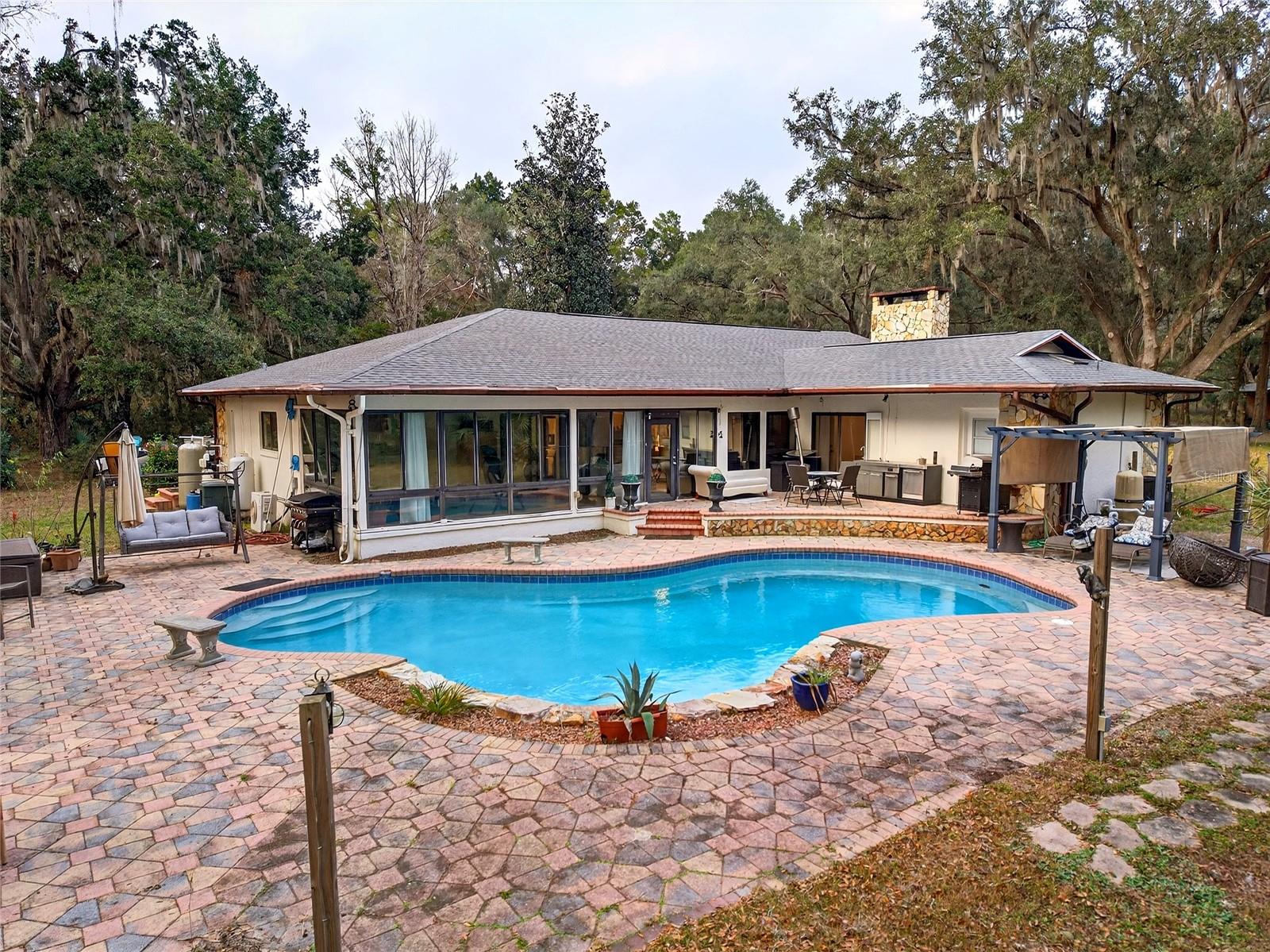 Think about it........15.17 acres, No Hoa, zoned A-1, pool, 2 RV hookups in place with room for a lot more, gated, easy access to main highway, loads of mature live oaks, and a barn ready for any of your imagination to put your passive income dreams into place here. Think rv opportunity, air bnb or vrbo, boarding of horses so close to wec with rv hook ups ......The growth in this area is one to be considered for long term success! Long winding and paved road leads to. Home(caretakers home) and barn/workshop/amenities center has 2025 new 30 year architectural roof, newer a/c system with UV light, water softener,and electric breaker panel. Exterior paint 2025. This inviting open floor plan features modern finishes and plenty of room to live or provide a great space for your passive income needs. The home has 2 living areas one with stone wood burning fireplace overlooking pool. 3 dining areas with inviting kitchen perfect for entertaining or events on site such as cooking classes or wine tasting!The kitchen has quartz countertop , massive island, stainless steel appliances, custom backsplash and a walk in pantry. This area overlooks the pool oasis as well with 2 level, step up down pool deck with plenty of room set up perfect for plenty of sun loungers and summer kitchen area. All bedrooms are spacious and have modern finishes in the bathrooms. Enclosed lanai is an extension on living area and is a peaceful area to take in the true beauty of this 15 acre property. There is more than meets the eye on this one. Think bigger picture, endless opportunities await you in this unique property. 15 mins to WEC, 10 minutes to Swampy's and state rainbow Springs park....