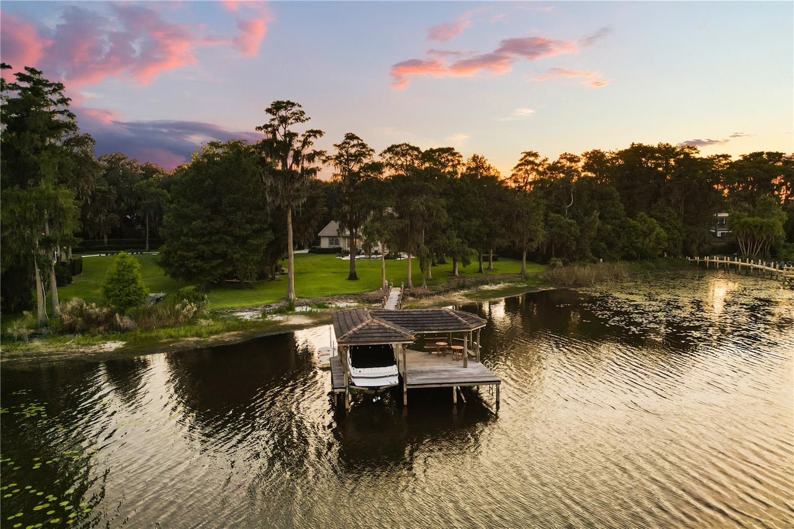 Tucked behind the gates of Crane's Point on the shores of 300-acre Lake Jessamine, this exceptional lakefront estate offers the perfect balance of luxury, privacy, and everyday livability. Bring the boat, the jet skis, and your favorite people. This is the waterfront lifestyle you've been waiting for!

From the moment you arrive, manicured landscaping and majestic trees welcome you home. Inside, soaring 14-foot ceilings with hand-hewn wood beams, rich hardwood floors, custom millwork, and expansive lake views create a warm yet sophisticated setting. Formal living and dining spaces are ideal for entertaining, while a gas fireplace, built-in bookcases  and walls of windows make every gathering feel connected to the beauty outside.

At the heart of the home, the completely remodeled chef's kitchen was designed to bring people together. A stunning 6' x 10' seamless quartzite island anchors the space, surrounded by custom cabinetry, premium Thermador appliances, a Rachiele workstation sink, wine refrigerator, separate beverage station with a sink and 2nd wine refrigerator, and abundant storage. Whether hosting holidays or enjoying a quiet morning coffee overlooking the lake, this kitchen truly is the center of the home.

The thoughtfully designed split-bedroom floor plan offers exceptional flexibility. The first-floor primary suite is tucked away for privacy and features a beautifully renovated spa-inspired bath. An additional bedroom, dedicated pool bath, and two secondary bedrooms connected by a Jack-and-Jill bathroom make everyday living effortless. Upstairs, a second primary suite captures panoramic lake views and includes a private office, mirrored fitness room, luxurious bath, and generous walk-in closet. With five bedrooms, four-and-a-half baths, and two primary suites, the layout is ideal for multigenerational living, extended family, or long-term guests.

Step outside and everyday life feels like a private resort. The custom heated lagoon-style pool and spa, dramatic Tennessee stone waterfall, travertine and porcelain decking, outdoor kitchen, pergola, and Sonos sound system create the perfect backdrop for everything from weekend barbecues to unforgettable celebrations. At the water's edge, a private dock with power, freshwater washdown, lakeside seating, and a double Wave Port jet ski lift makes it easy to spend your days boating, paddleboarding, fishing, or simply enjoying sunset views across Lake Jessamine.

Additional features include a three-car garage with epoxy floors, new interior and exterior paint, plantation shutters, copper gutters, updated electrical, commercial-grade water heater, new irrigation pump, updated septic system, French drains, and extensive landscape lighting.

Located just minutes from Downtown Orlando, Orlando International Airport, hospitals, dining, and major roadways, this one-of-a-kind luxury waterfront home offers the rare opportunity to enjoy resort-style lakefront living without sacrificing convenience. Every detail has been thoughtfully curated so you can spend less time maintaining a home and more time making memories! Schedule your private showing today!