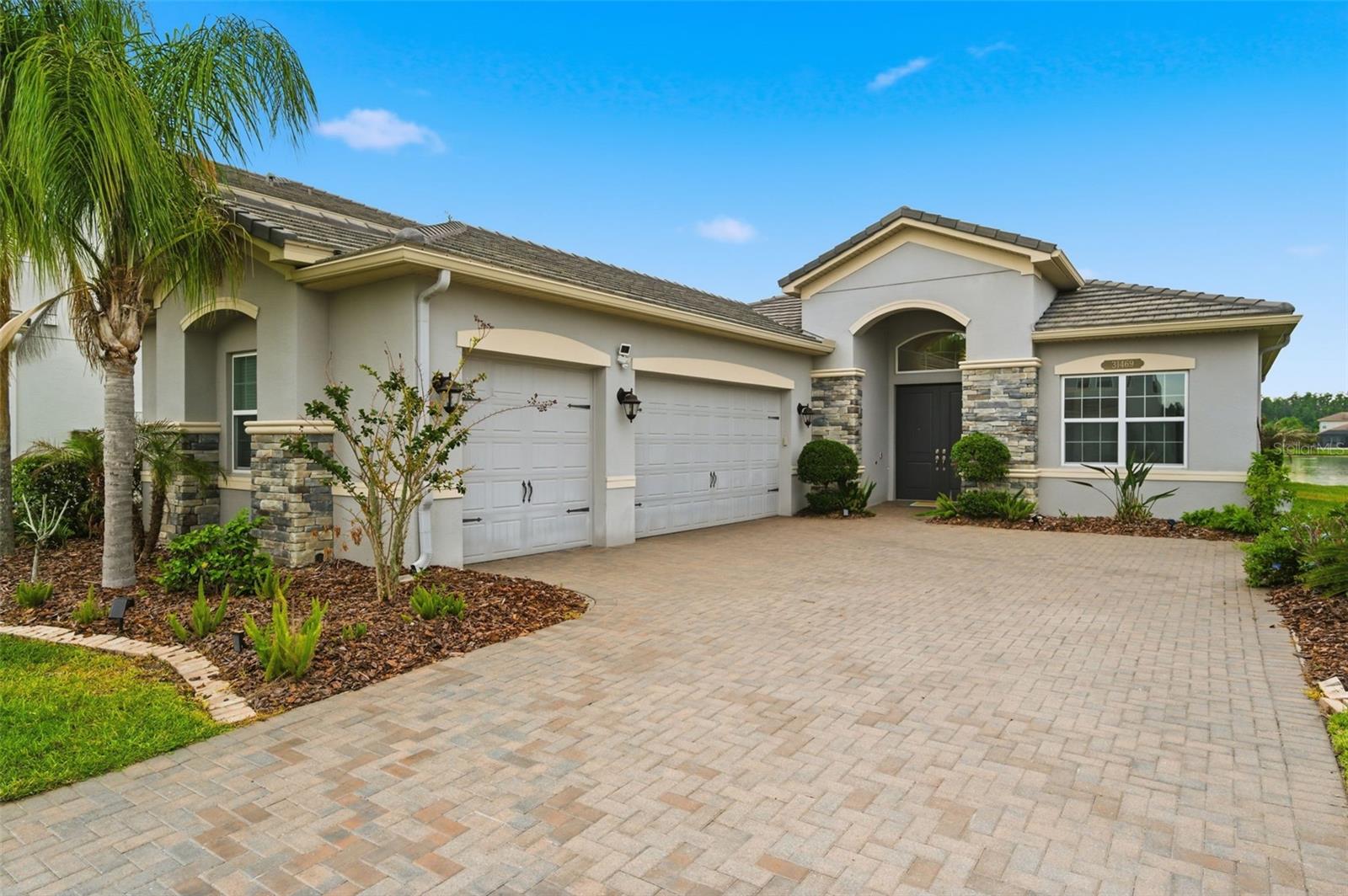 Located within the prestigious The Ridge at Wiregrass Ranch, this impeccably upgraded residence offers approximately 2,500 square feet under air with 3 bedrooms, 3 full bathrooms, a private den, and a spacious 3-car garage, all perfectly positioned on a picturesque pond view homesite. Designed with an elevated blend of luxury, comfort, and functionality, this home showcases exceptional indoor-outdoor living in one of Wesley Chapel’s premier gated communities. A grand double-door entry welcomes you into an expansive open-concept floor plan featuring wood-look tile flooring, crown molding, surround sound, designer finishes, and a custom wet bar ideal for entertaining. The gourmet kitchen serves as the centerpiece of the home and is appointed with quartz countertops, extended cabinetry, glass inlay accents, a gas cooktop, statement chimney hood, double wall ovens, and an oversized island overlooking the main living and dining spaces. The outdoor living area was thoughtfully designed to maximize the stunning water views and Florida lifestyle. The extended screened lanai and patio create a seamless extension of the home and feature a custom outdoor kitchen, tranquil water feature, fire pit, and multiple spaces for relaxing and entertaining while overlooking the serene pond setting. The luxurious primary suite offers a private retreat, while the split-bedroom floor plan and separate den provide both flexibility and privacy. Combining designer upgrades, architectural detail, and an exceptional homesite, this move-in-ready residence delivers refined living within the sought-after community of The Ridge at Wiregrass Ranch. Residents of The Ridge at Wiregrass Ranch enjoy an exceptional resort-style lifestyle with world-class amenities including a zero-entry pool, lap pool, water slide, splash/play area, professional tennis courts, indoor sports court, outdoor basketball courts, sand volleyball court, fitness center, fitness studio, gathering room, and a 24-hour guard-gated entrance. HOA fees include lawn and grounds maintenance for added convenience and low-maintenance living. Ideally located near top-rated schools, exceptional healthcare, premier shopping and dining, and convenient highway access, The Ridge at Wiregrass Ranch continues to be one of Wesley Chapel’s most sought-after luxury communities.