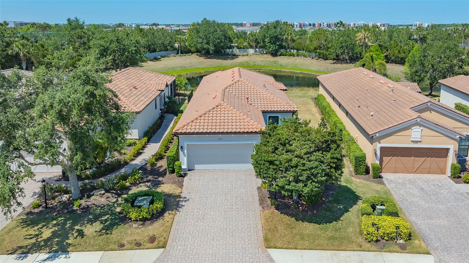 Welcome to a truly one-of-a-kind opportunity to own a beautifully upgraded residence in the highly sought-after Esplanade at Lakewood Ranch, where everyday living feels like a luxury resort escape. Perfectly suited as a full-time residence or an ideal seasonal getaway to escape harsh northern winters, this stunning 2-bedroom, 2-bath home with a spacious den is ideally positioned on a private homesite with serene water views, surrounded by lush, meticulously maintained landscaping. From the moment you step inside, the pride of ownership and attention to detail are unmistakable, highlighted by an open-concept design with soaring tray ceilings, elegant crown molding, tile flooring throughout the main living areas, and abundant natural light. The gourmet kitchen serves as the heart of the home, featuring granite countertops, 42-inch upper cabinets, a tile backsplash, black stainless steel appliances including a brand-new refrigerator, a gas range, and a generous breakfast bar that flows seamlessly into the expansive living and dining spaces, making it perfect for both everyday living and entertaining. Step outside to the extended screened lanai, enhanced with premium panoramic picture-window screening, stamped concrete flooring, retractable sunshades, and beautiful Nebula LED lighting, creating an inviting space to unwind while enjoying peaceful water views. A built-in gas line is already in place for a future outdoor kitchen, making this an ideal setting for outdoor entertaining. The private owner’s suite is a tranquil retreat with a bay window sitting area, dual vanities, a large walk-in shower, and a custom-designed walk-in closet, while the guest bedroom offers comfort and privacy with its own en-suite bath. The versatile den, featuring double pocket doors and a transom window, is perfect as a home office, flex space, or optional third bedroom. This home truly stands apart with hurricane-impact glass windows installed in 2021 with a transferable warranty, an exceptional and valuable upgrade not found in many homes, providing enhanced storm protection, energy efficiency, and peace of mind. Additional improvements include a new HVAC system installed in 2022, a tankless hot water heater, central vacuum with kitchen toe-kick, surround sound speakers in the living room and lanai, and numerous thoughtful enhancements throughout. The oversized two-car garage features epoxy-coated floors, built-in shelving, and additional storage space, while the paver driveway and professionally lit walkway with uplighting add to the home’s welcoming curb appeal. The CDD bond has been paid in full, and ground maintenance is included in the HOA fees. Pets and fencing are permitted with size restrictions, offering added flexibility. Residents of Esplanade enjoy an unmatched array of resort-style amenities including tennis, pickleball, bocce ball, two fitness centers, resistance and lagoon-style pools, a full-service spa, outdoor grilling areas, fire pits, two dog parks, and the popular Tiki Bar. The state-of-the-art Culinary Center offers multiple dining options along with cooking classes, while golf enthusiasts can take advantage of the optional 18-hole championship golf course set across more than 600 acres of beautiful Florida landscape. All of this is just minutes from I-75, Lakewood Ranch Medical Center, Waterside Place, Lakewood Ranch Main Street, University Town Center, world-class shopping and dining, and the stunning Gulf Coast beaches.