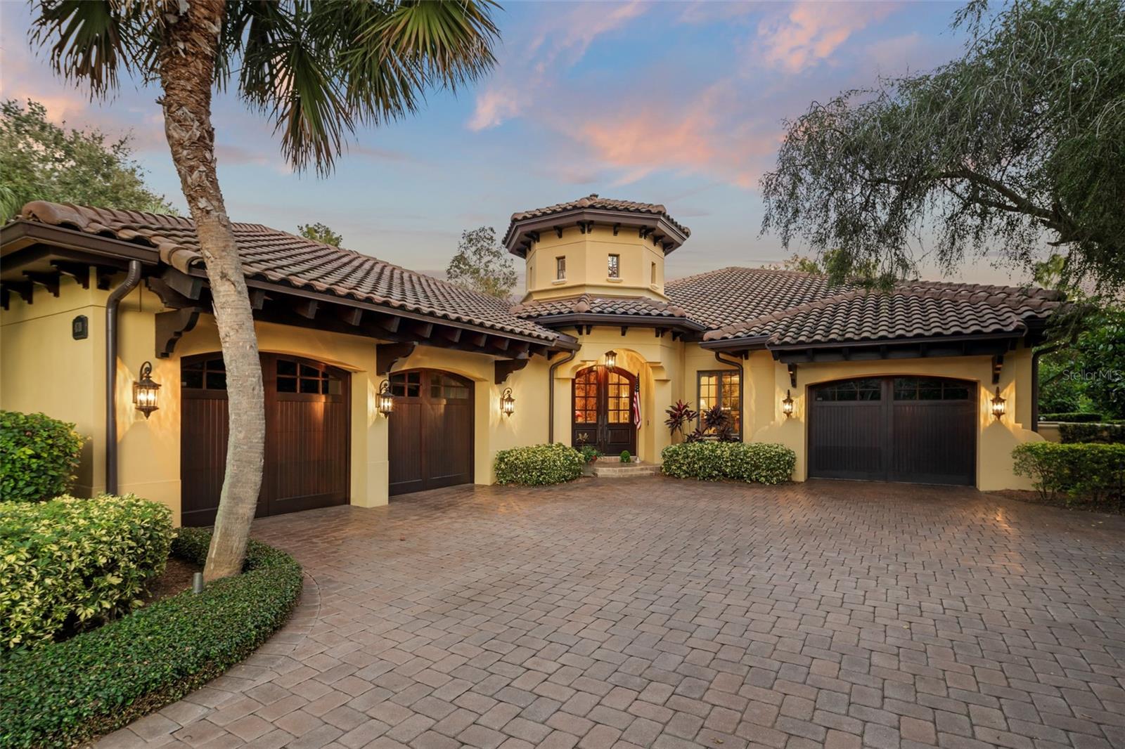 Nestled within the exclusive Gardens of Isleworth enclave within Isleworth Golf & Country Club, this exquisite residence exemplifies refined Florida living. Crafted by Pellegrini Homes with professionally designed interiors, the single-story home seamlessly blends architectural sophistication with inviting comfort. A brick paver motor court introduces the residence, where a gracious custom arched French entry door sets the tone for the elegance within. The formal foyer makes a lasting impression with its soaring octagonal ceiling accented in tongue-and-groove woodwork. Inside, the formal living room—currently styled as a music salon—showcases a faux-painted garden ceiling and a custom brick wine nook, adding artistic charm and warmth. Throughout the home, travertine floors and curated details complement a spacious open plan, lending to the home's exceptional design and craftsmanship. Framed by reclaimed rustic wood beams and sliding glass doors, the family room flows naturally to the courtyard pool, creating effortless indoor-outdoor living. The center-island kitchen serves as a culinary showcase with custom cabinetry and premium appliances by Viking, Sub-Zero, and GE Monogram, while the adjoining casual dining area offers views of the pool and lush surroundings. The thoughtfully designed layout includes three bedrooms, one of which is a private cabana suite opening directly to the pool—ideal for guests or quiet retreat. The primary suite features a large bedroom, dual closets and a beautifully finished bath.  Beyond the courtyard, a patio with pergola overlooks serene pond views,  providing yet another setting for relaxation and entertaining. Centered around its picturesque courtyard pool with fireplace, summer kitchen, and hot tub, this remarkable residence offers both privacy and elegance in perfect balance—an exceptional opportunity to live beautifully within one of Isleworth's most coveted enclaves.