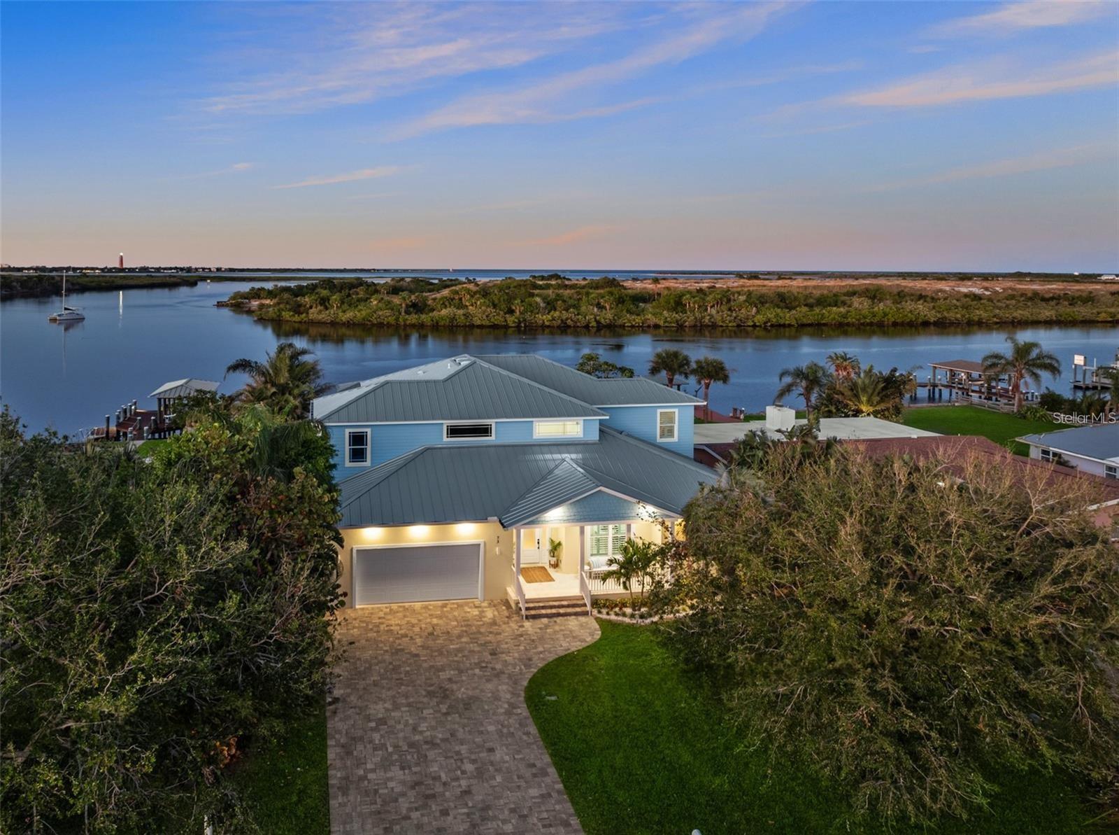 Introducing a rare opportunity to own a stunning, nearly new construction home in New Smyrna Beach, offered for the first time. Perfectly situated on 75 feet of deep water frontage, this boater's dream offers breathtaking views of the historic lighthouse and quick access to the inlet for your next offshore adventure. BOAT & JET SKI'S Can be included and the seller will entertain OWNER FINANCING with the right terms.

With 5 spacious bedrooms, a dedicated home office which could be a 6th bedroom, and a luxurious in-home movie theater, this estate is thoughtfully designed for both relaxation and entertainment. The open-concept living space features modern upgrades throughout, including a chef's kitchen with captivating lighthouse views, where culinary creations and memorable family moments await.

Step outside to your private oasis, complete with an incredible pool, perimeter overflow spa, and a covered boathouse with a lift. Whether you're hosting a game day gathering, fishing off the dock, or simply soaking in the tranquil riverfront setting, this home is the ultimate entertainer's haven and is being offered professionally decorated, furnished & turn key.

Set on an elevated concrete block foundation with impact windows and a metal roof, this meticulously designed home offers peace of mind and durability. Located near the vibrant shops and restaurants of downtown New Smyrna Beach, yet tucked away in the privacy of your own waterfront estate, the location is unparalleled.

Experience the perfect blend of luxury, functionality, and Florida waterfront living. Schedule your showing today and begin your journey to living the ultimate riverfront lifestyle!